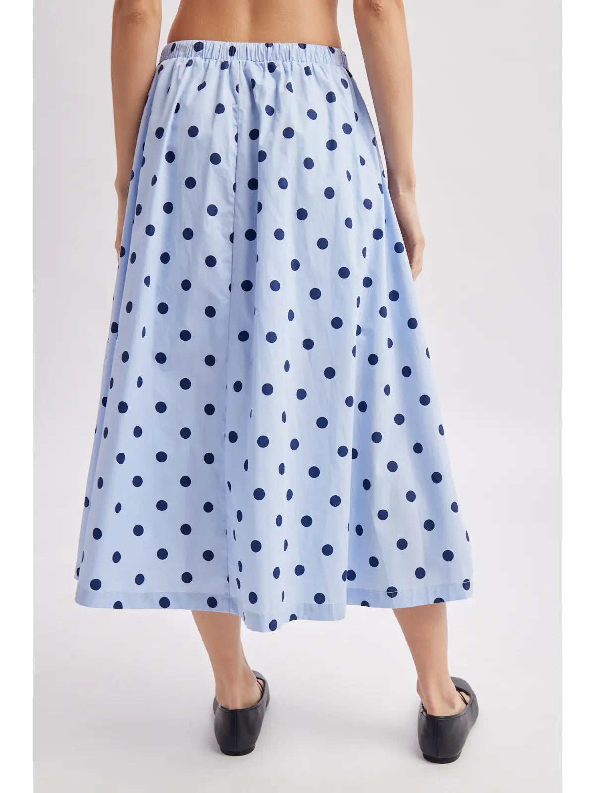 A light blue midi skirt with a navy blue polka dot pattern, shown on a model from the back against a light gray studio background.