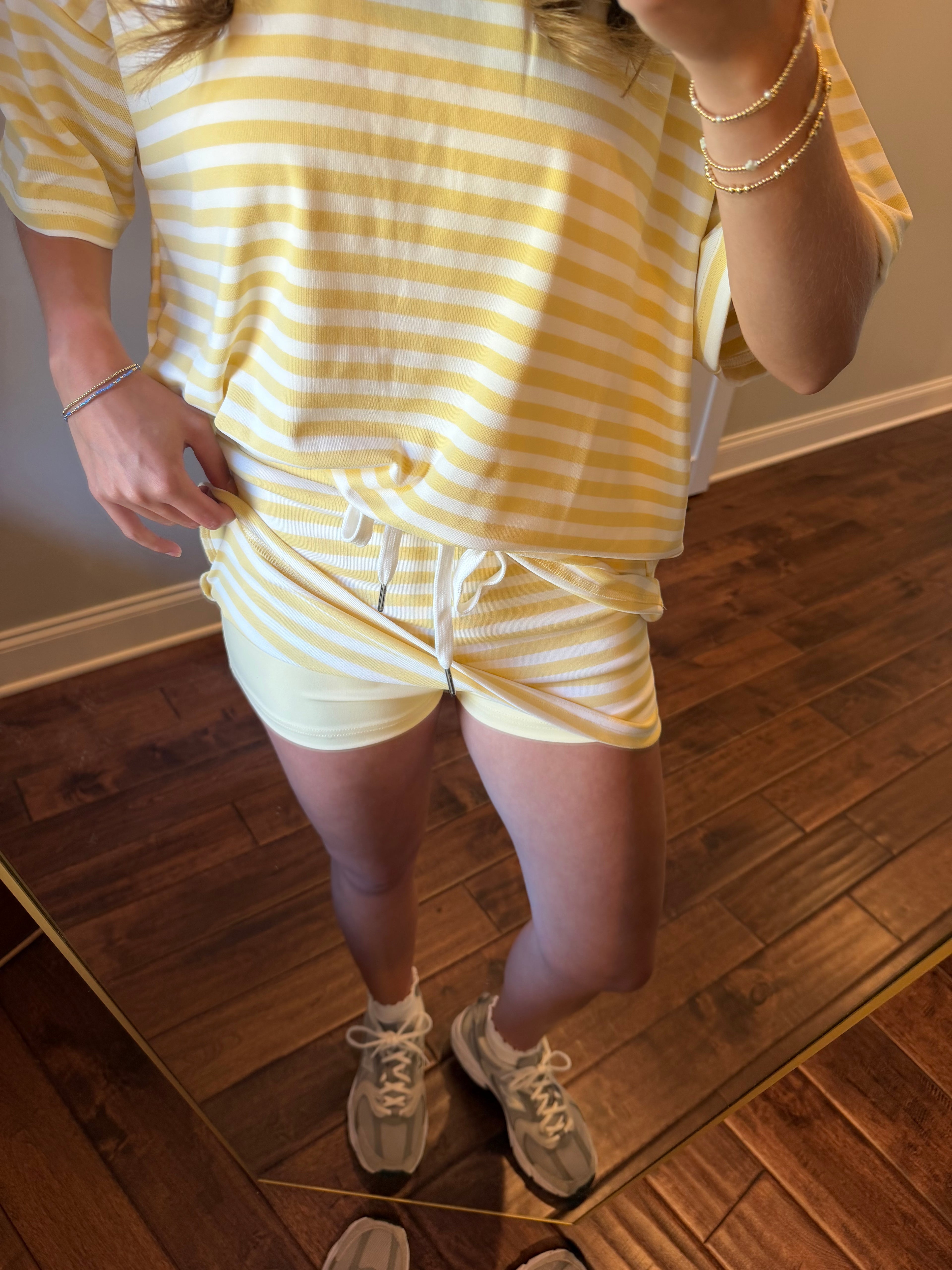 Person wearing a yellow and white striped dress standing on a wooden floor.