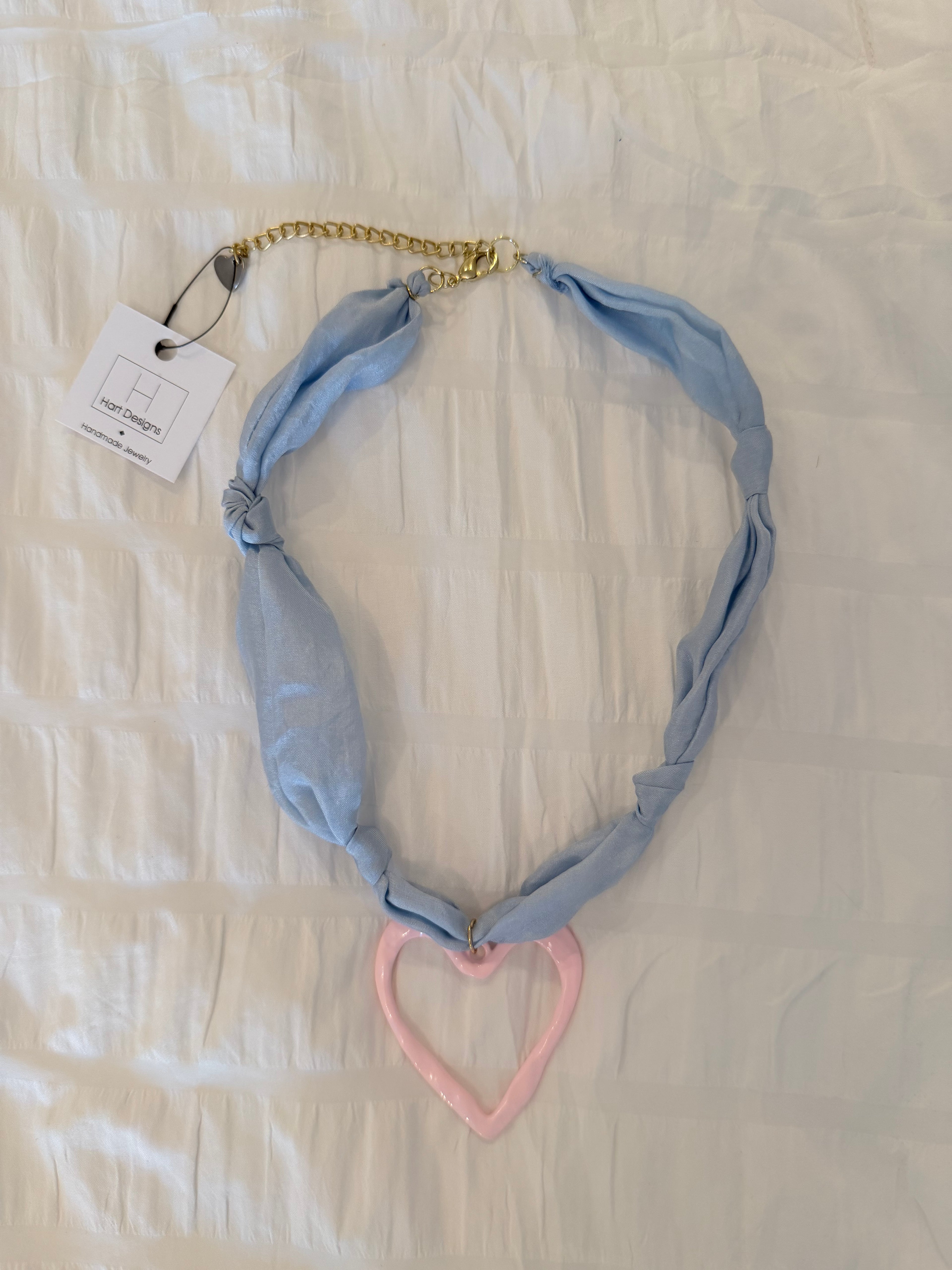 Necklace with a blue chain and pink heart on a light background