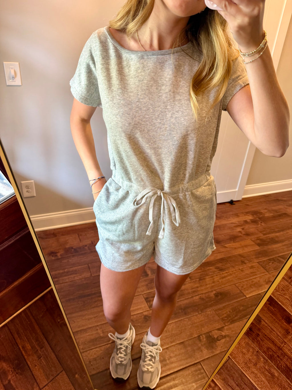 Person wearing a gray romper in a room with wooden flooring.