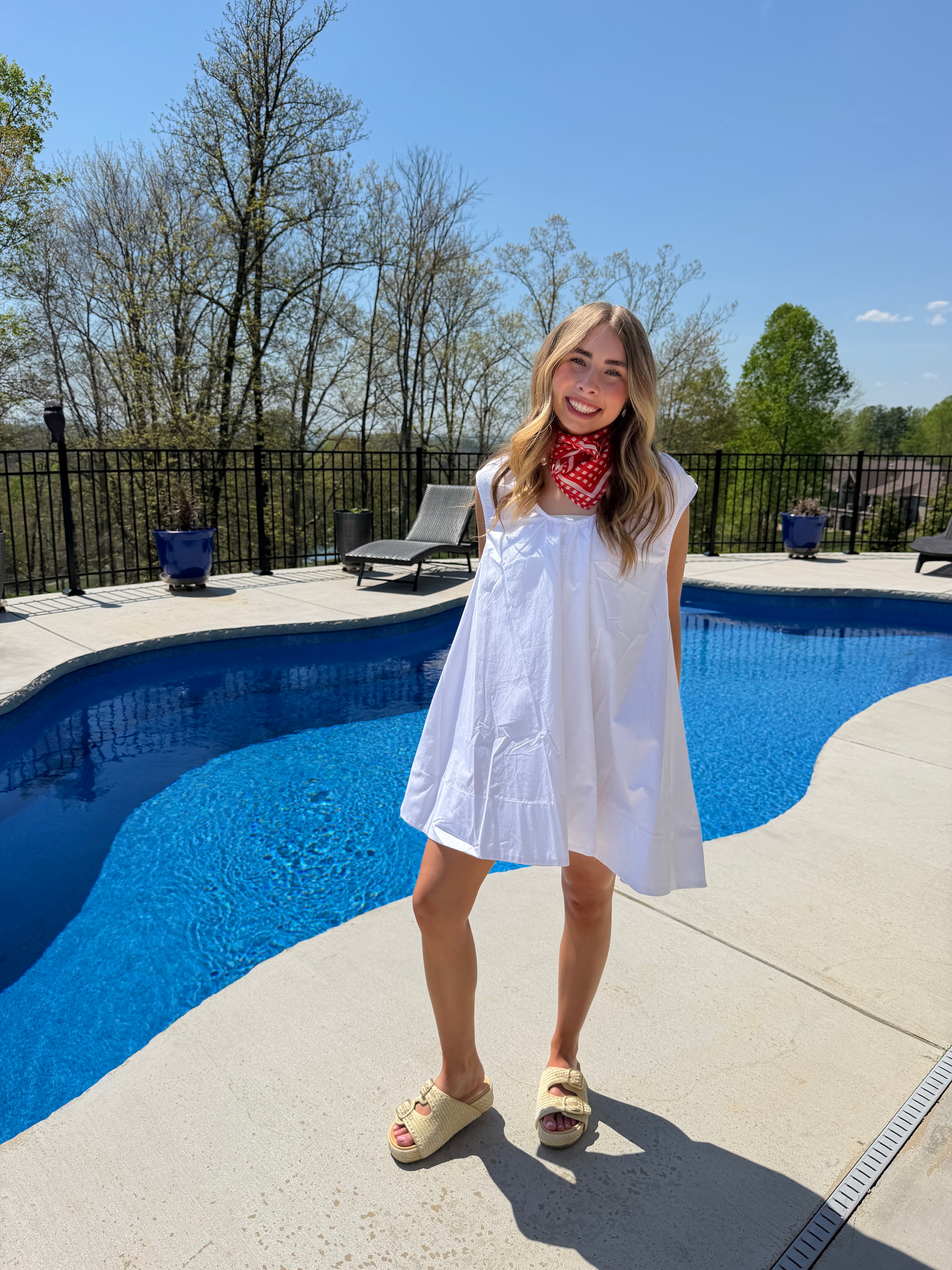 Person standing by a pool with a clear blue sky