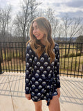 Woman wearing a navy floral dress standing outdoors with trees and sky in the background