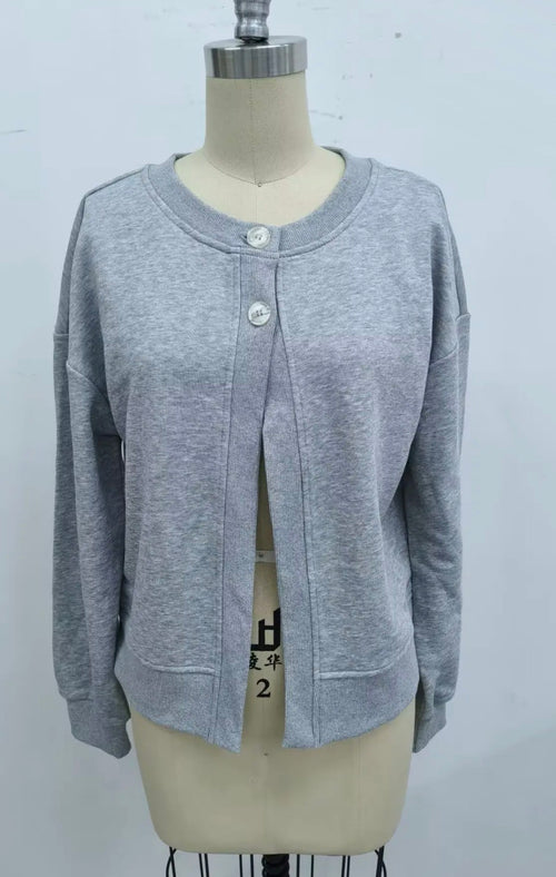 A light gray heathered knit cardigan sweater displayed on a beige dress form mannequin. The cardigan features a crew neck, three silver buttons, and a front split opening.