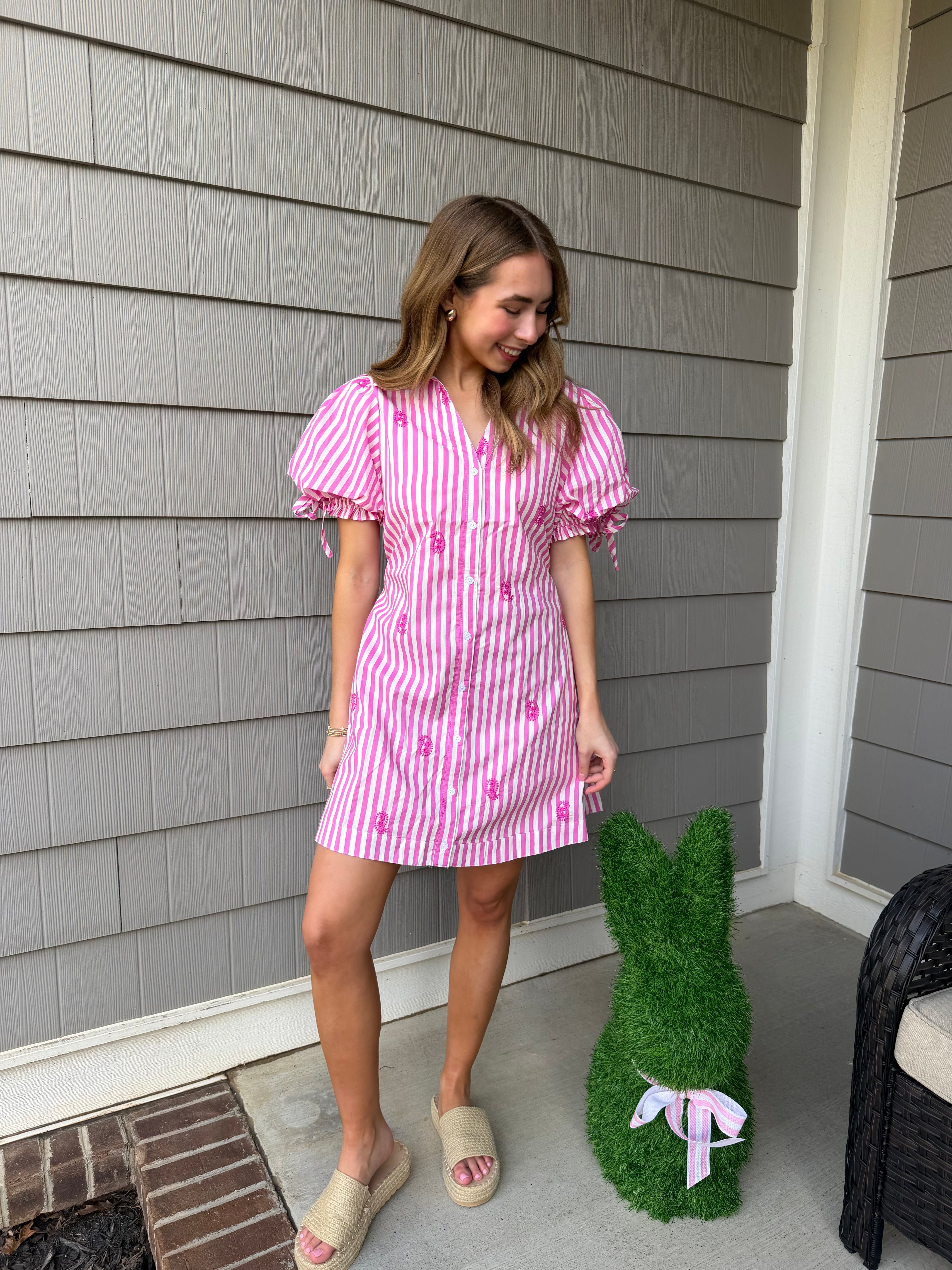 Woman in a pink dress standing on a gray wooden deck