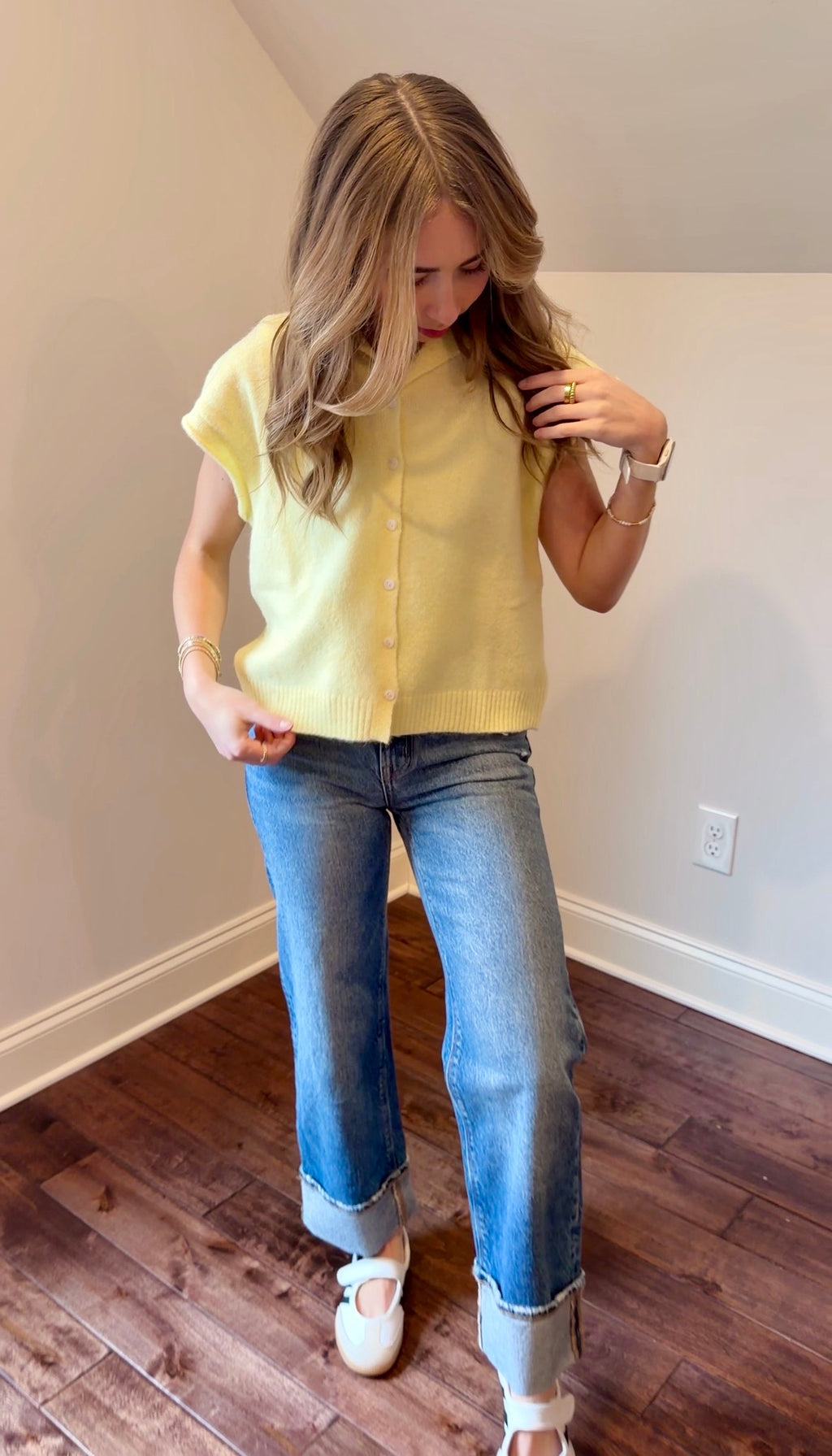 Woman wearing a yellow top and blue jeans indoors.