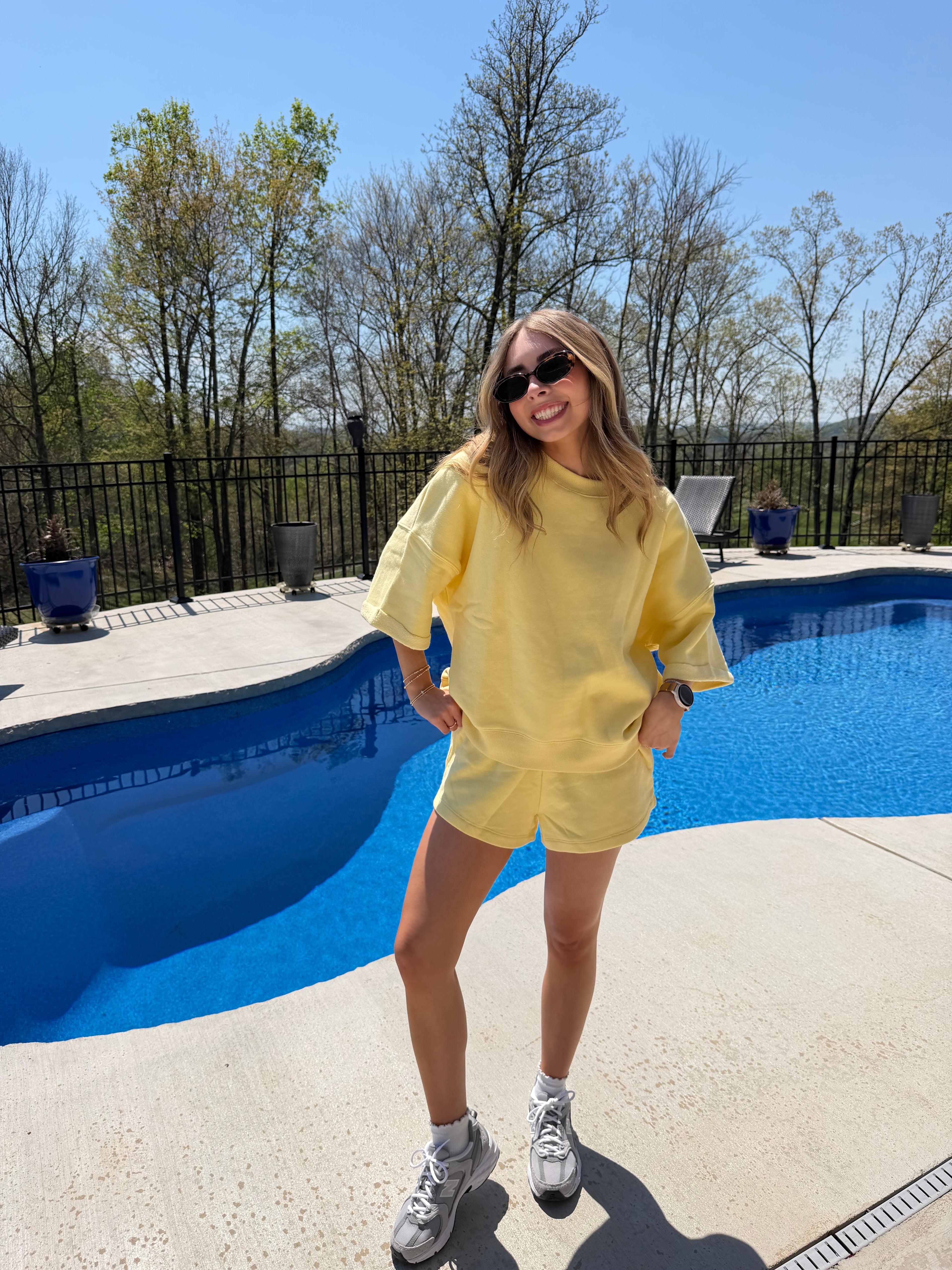 Person in a yellow matching set standing by a pool on a sunny day