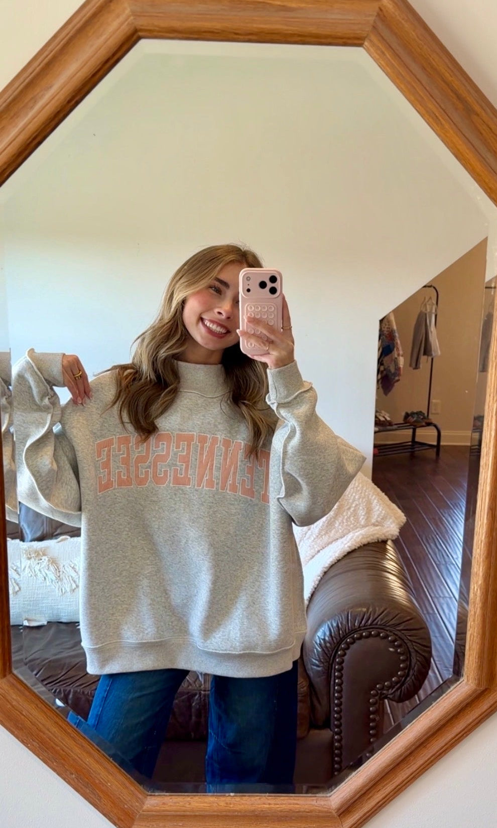 Person wearing a gray sweatshirt with 'Tennessee' printed on it, taking a mirror selfie.