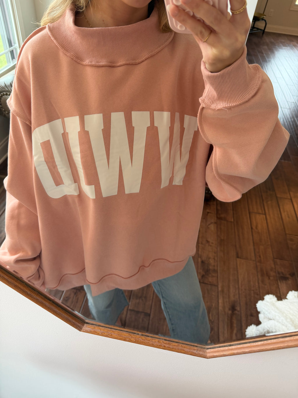 Pink sweatshirt with white text on a wooden surface