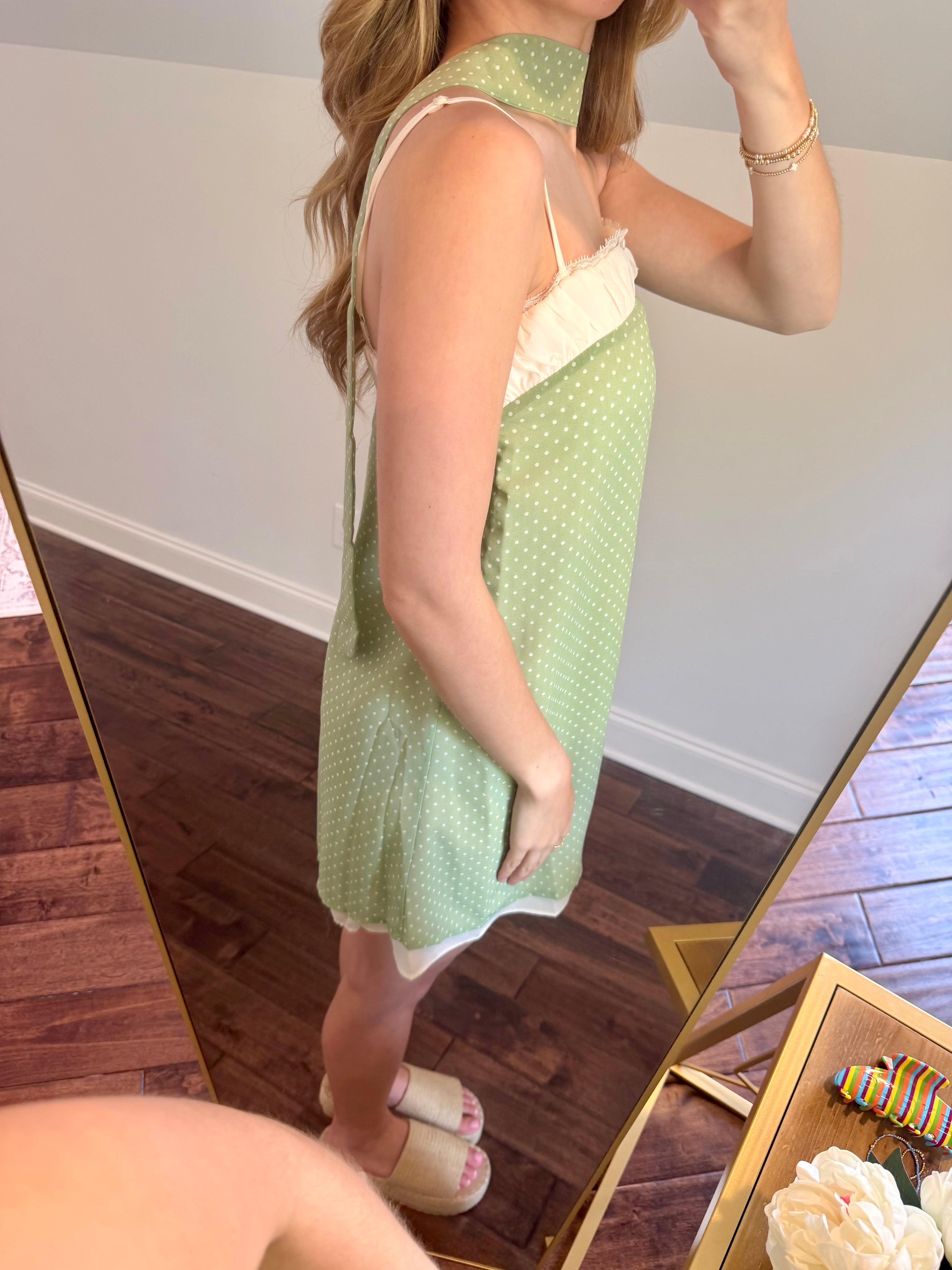 Woman wearing a green dress with white polka dots in a room.