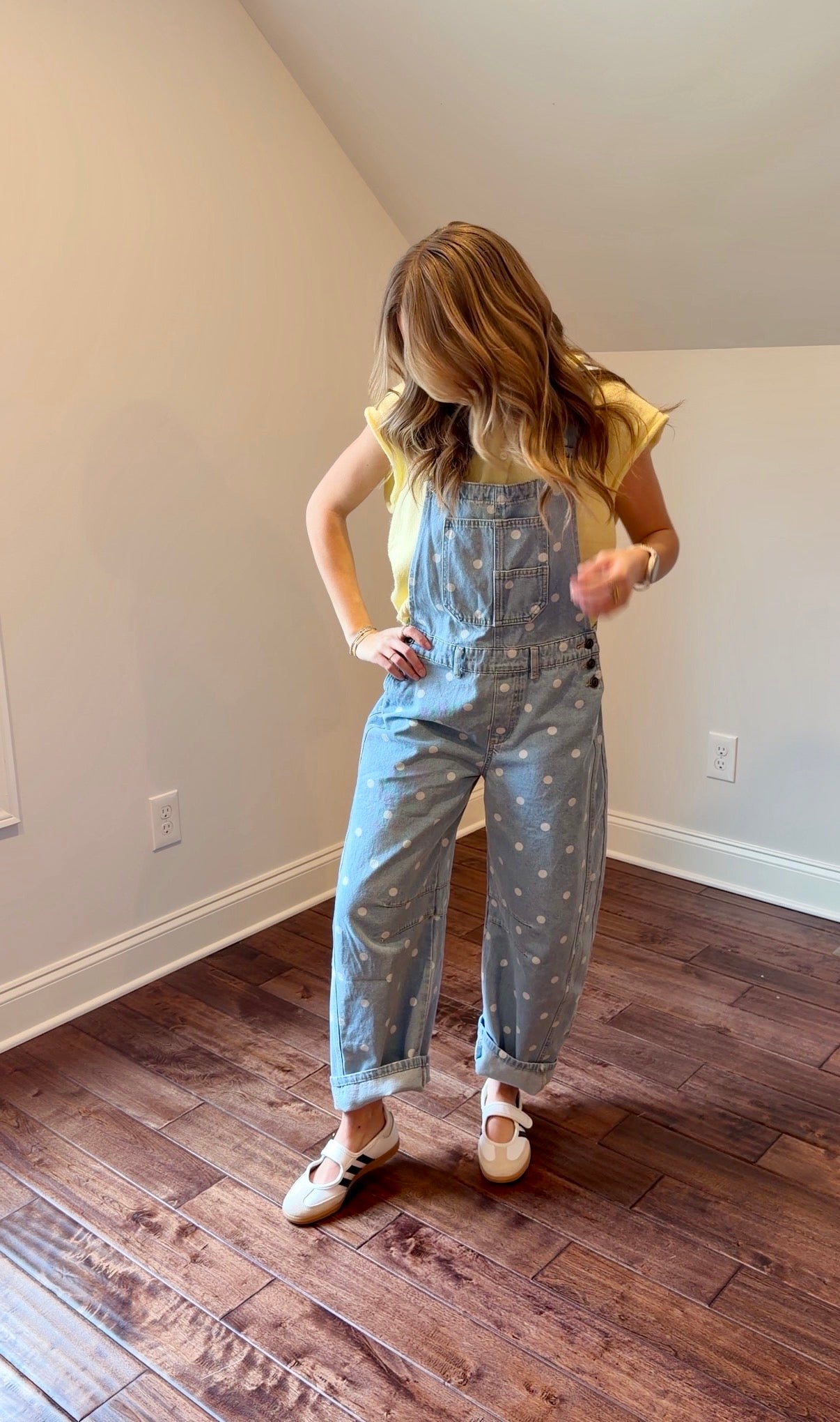 Person wearing a light blue polka dot jumpsuit standing on a wooden floor.