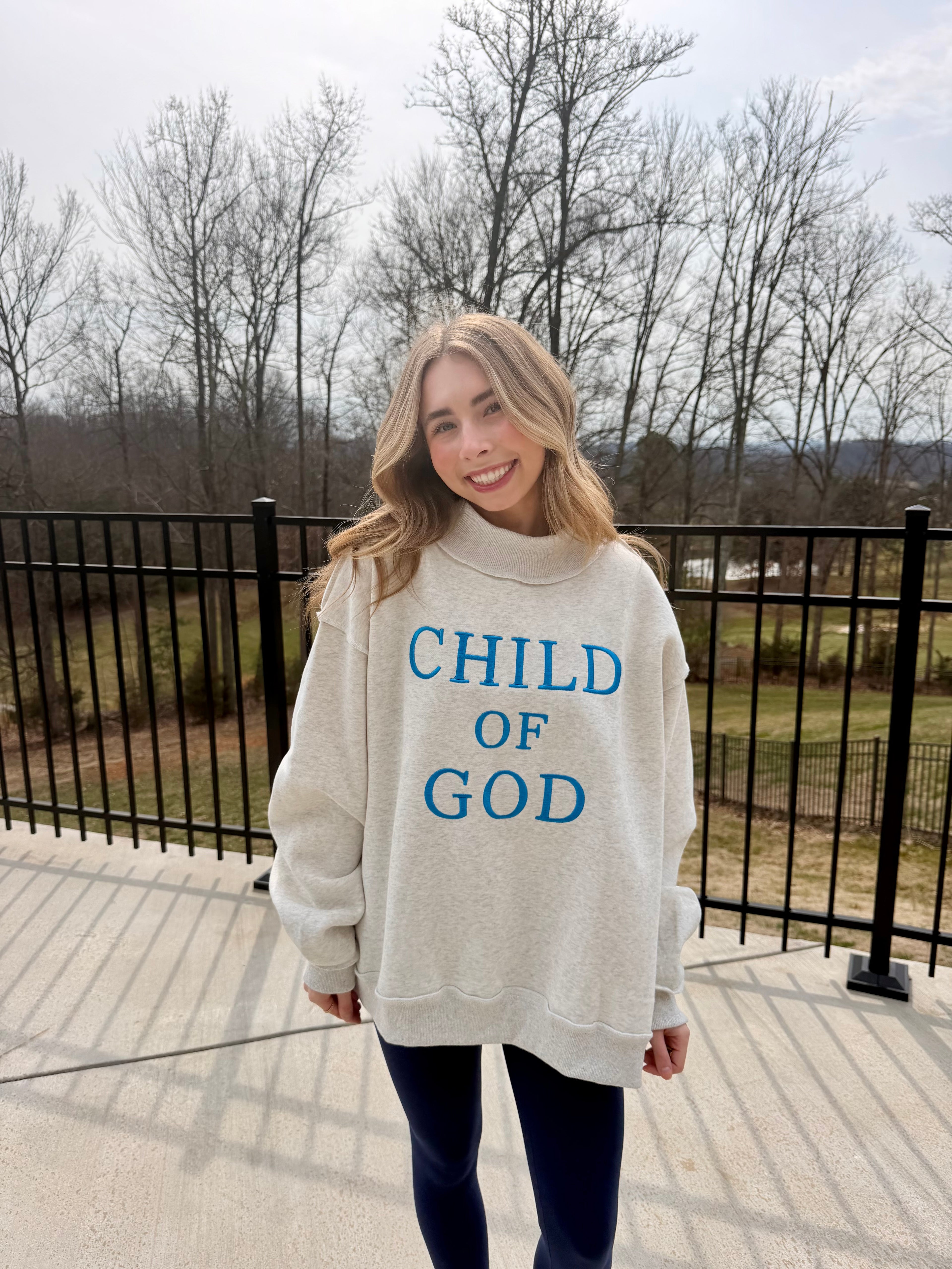 Woman wearing a 'Child of God' sweatshirt outdoors