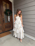 Woman in a white dress standing in front of a wooden door with a gray wall background
