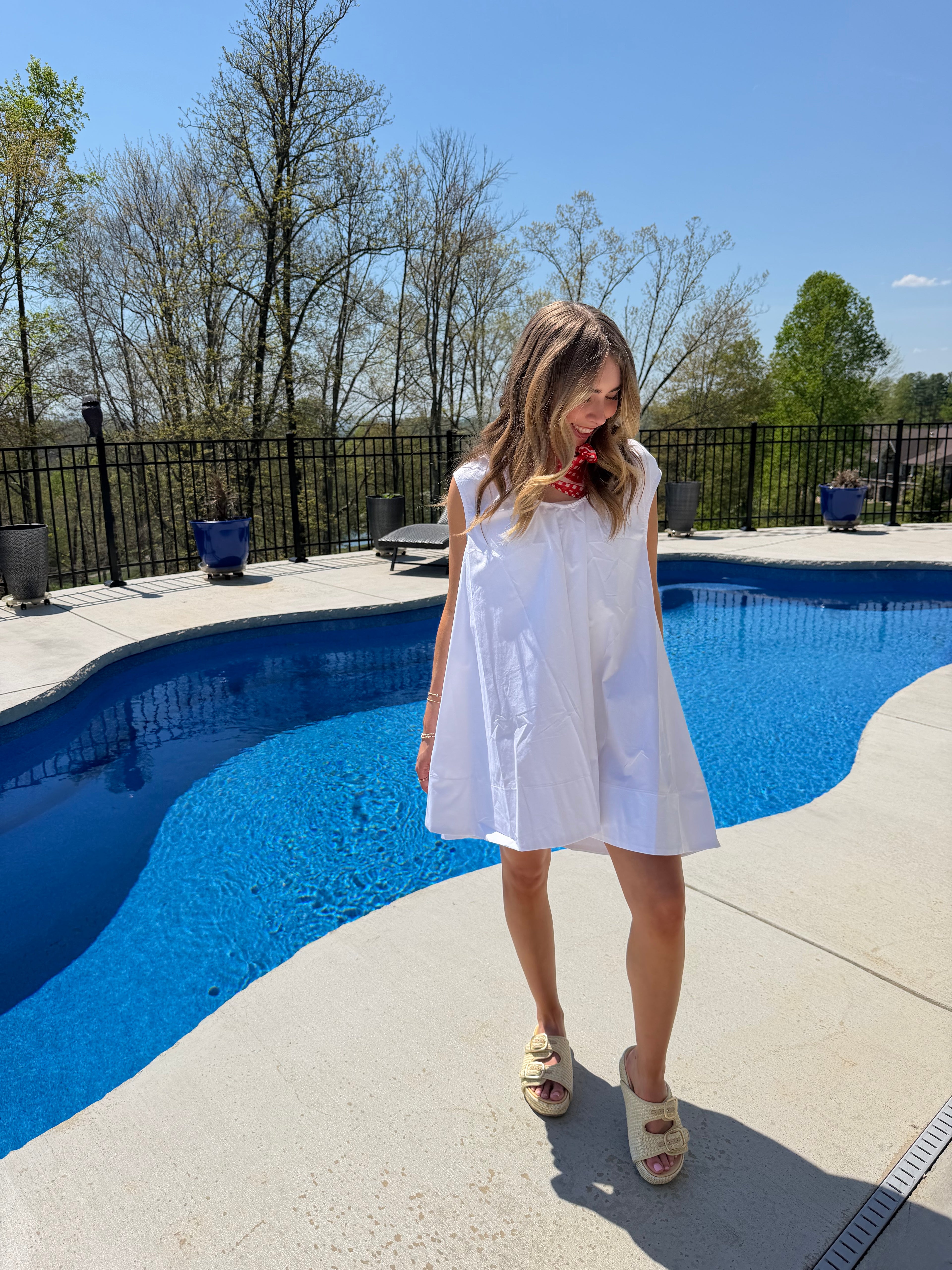 Person standing by a pool with a clear blue sky
