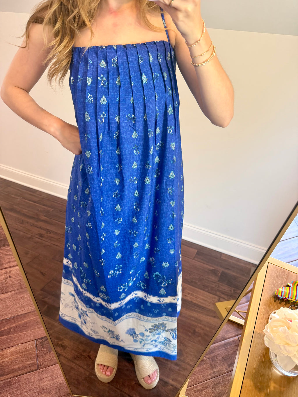 Person wearing a blue dress with white patterns in front of a mirror.