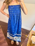 Person wearing a blue dress with white patterns in front of a mirror.