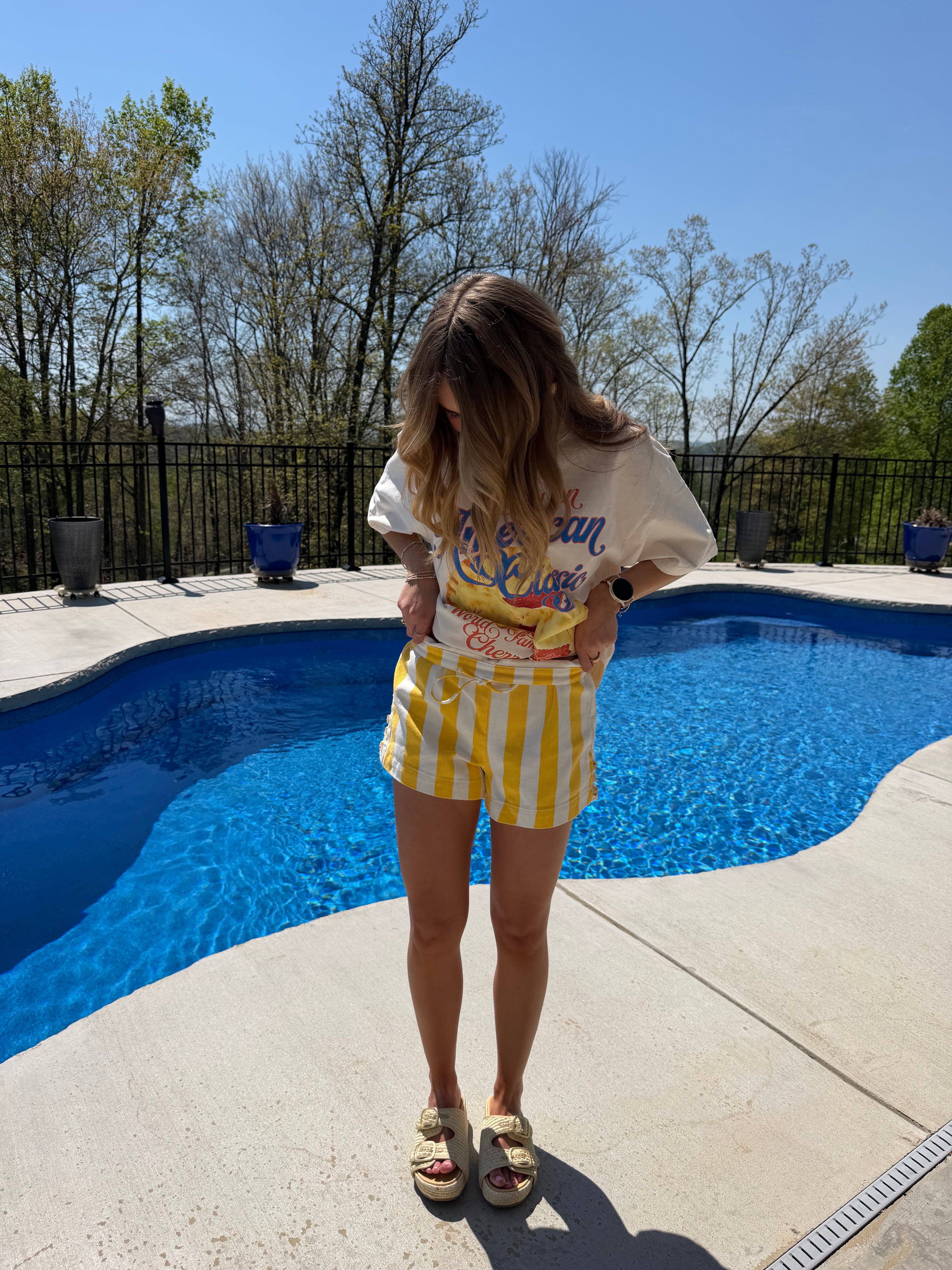 Person standing by a pool wearing a yellow and white outfit with text on it.