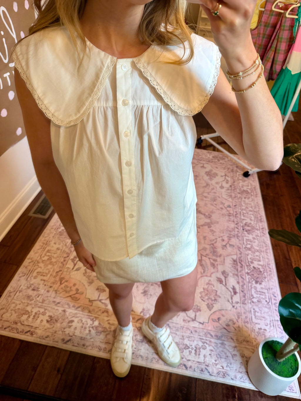 Person wearing a light-colored blouse with a lace collar in a home setting.