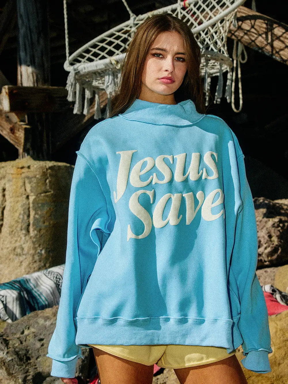 Person wearing a blue hoodie with 'Jesus Save' text outdoors.