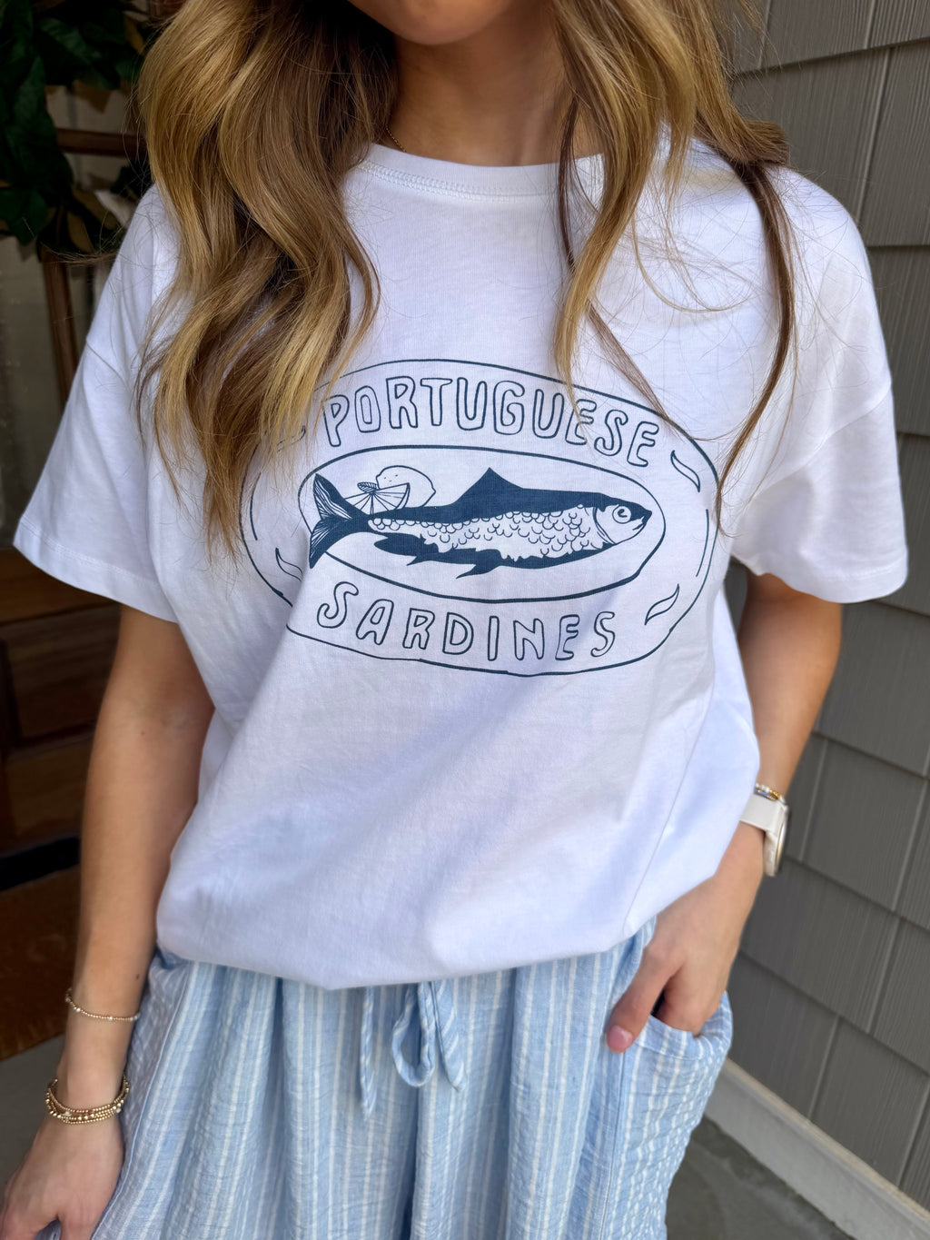 Person wearing a white t-shirt with a graphic design outdoors.