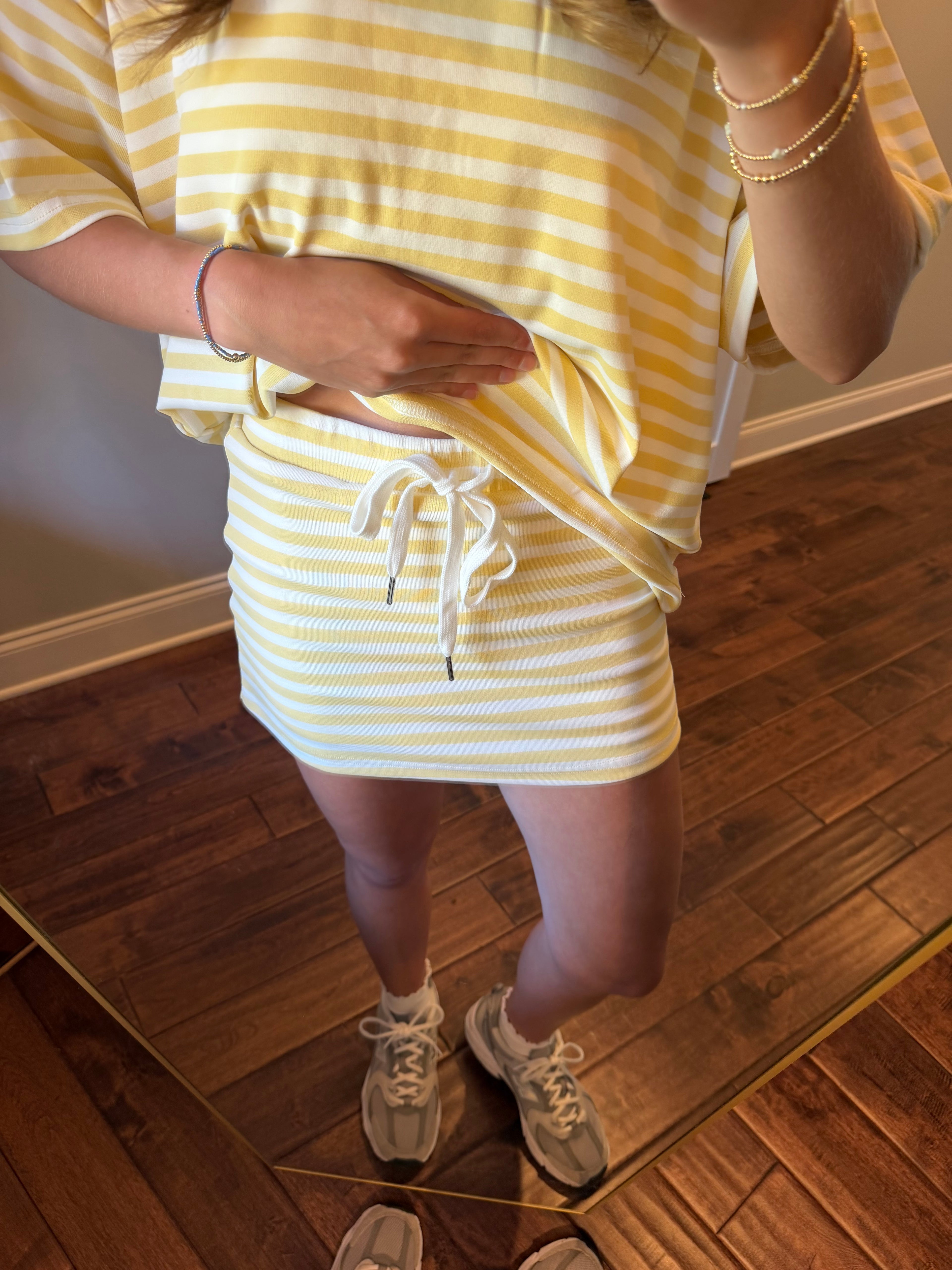 Person wearing a yellow and white striped outfit standing on a wooden floor.