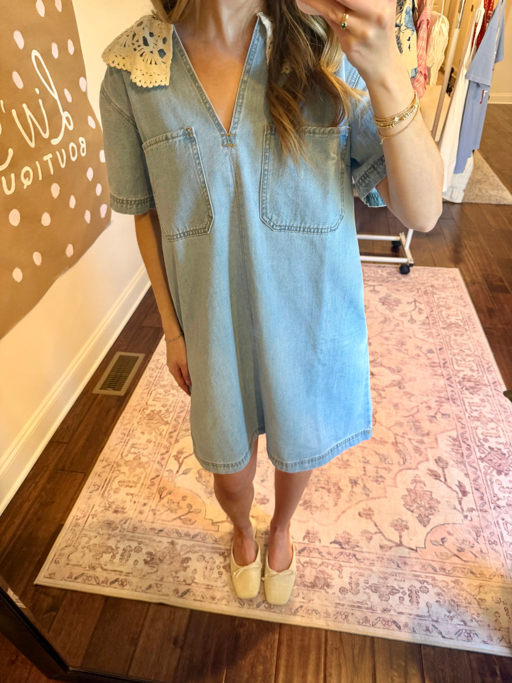 Woman taking a mirror selfie wearing a light blue dress in a home setting.