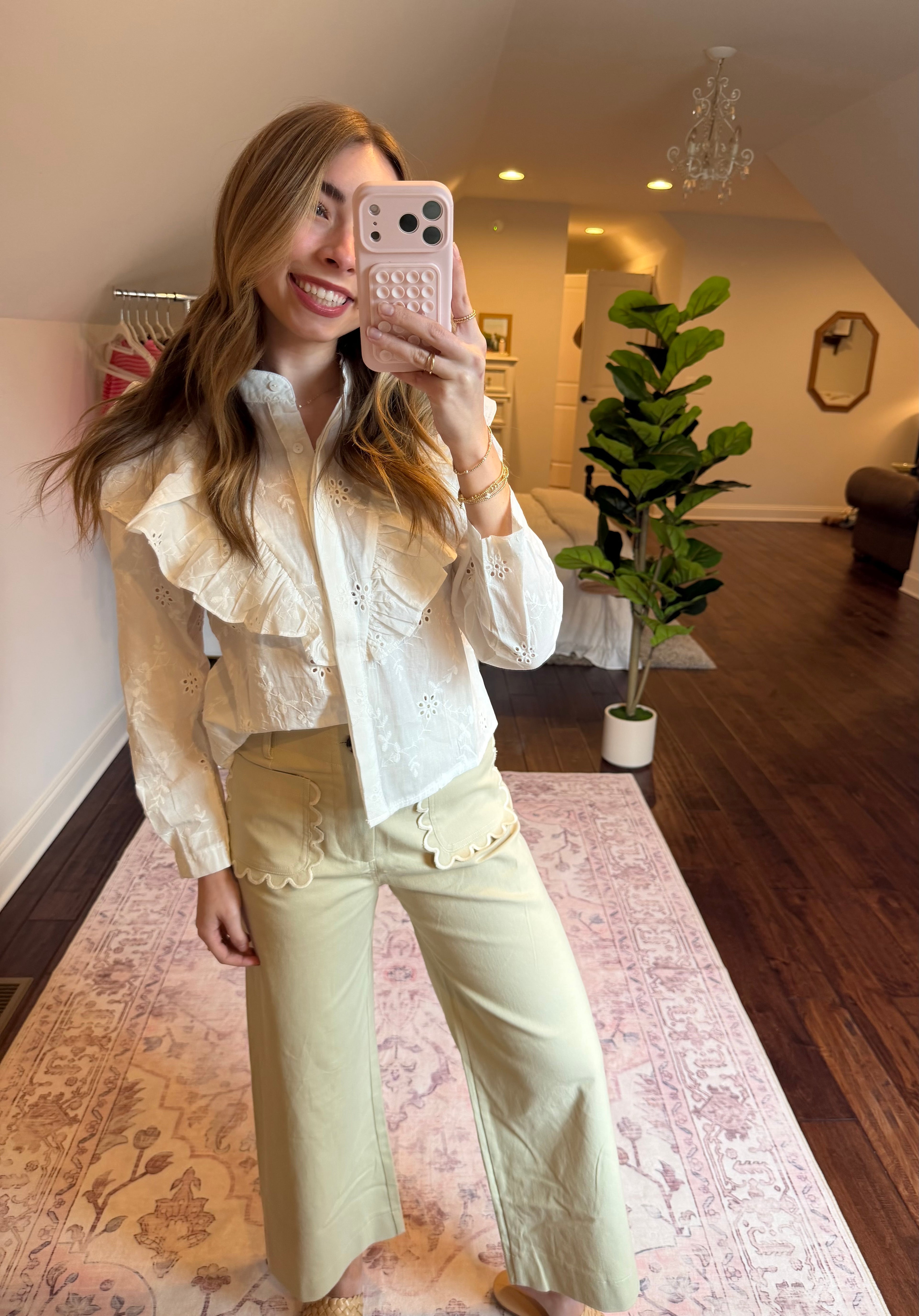 Person wearing a white blouse with beige pants and shoes on a patterned rug.