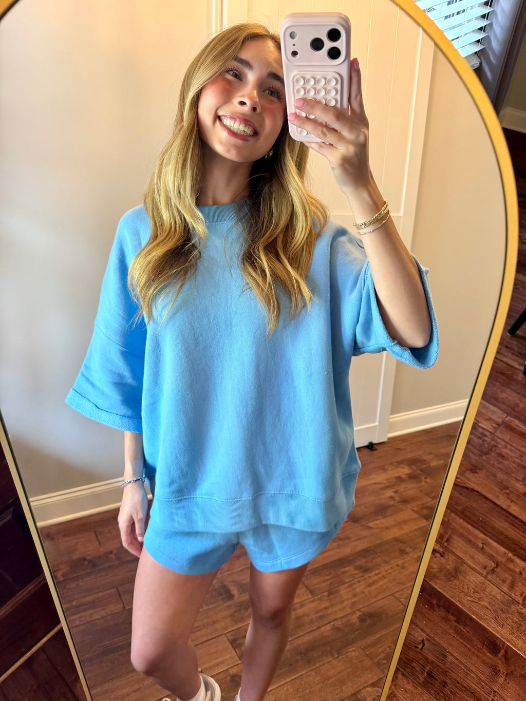 Person taking a mirror selfie wearing a light blue outfit.