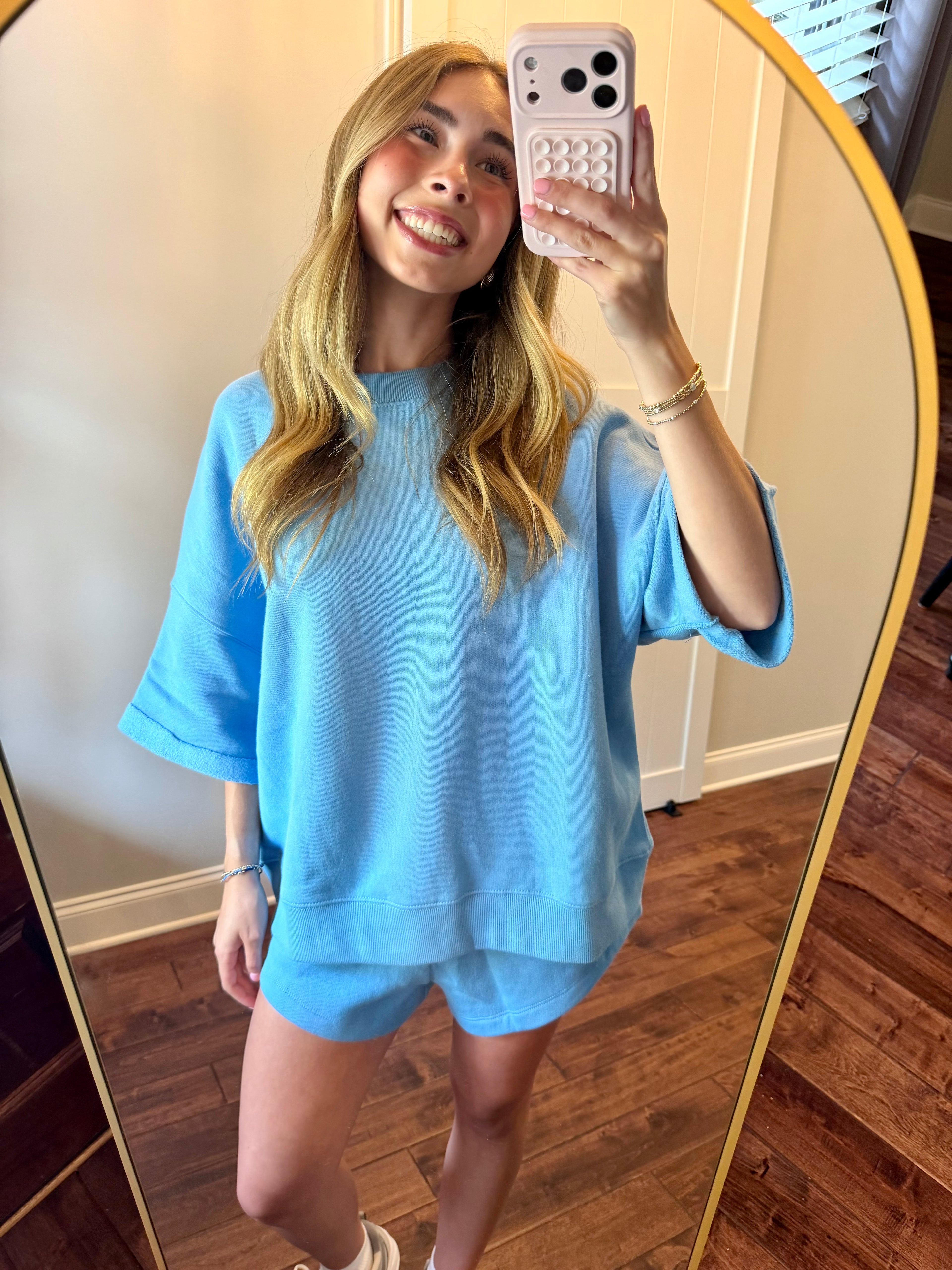 Person taking a mirror selfie wearing a light blue outfit.