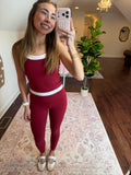 Woman taking a mirror selfie wearing a red outfit with white trim in a room.