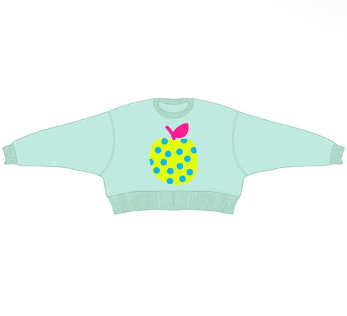 A light mint green long-sleeve crewneck sweater featuring a stylized yellow pineapple graphic on the chest with blue polka dots and a pink leaf.