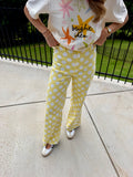 A person standing outdoors on a concrete patio wearing yellow pants with large white polka dots and a white graphic T-shirt with colorful starfish and the words 'bright ideas'.