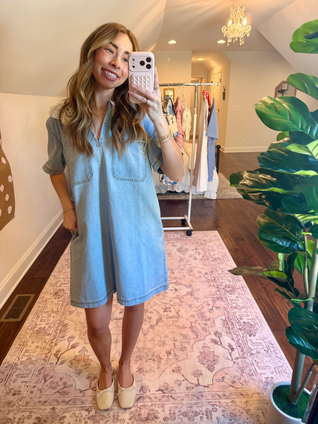 Woman taking a mirror selfie wearing a light blue dress in a home setting.