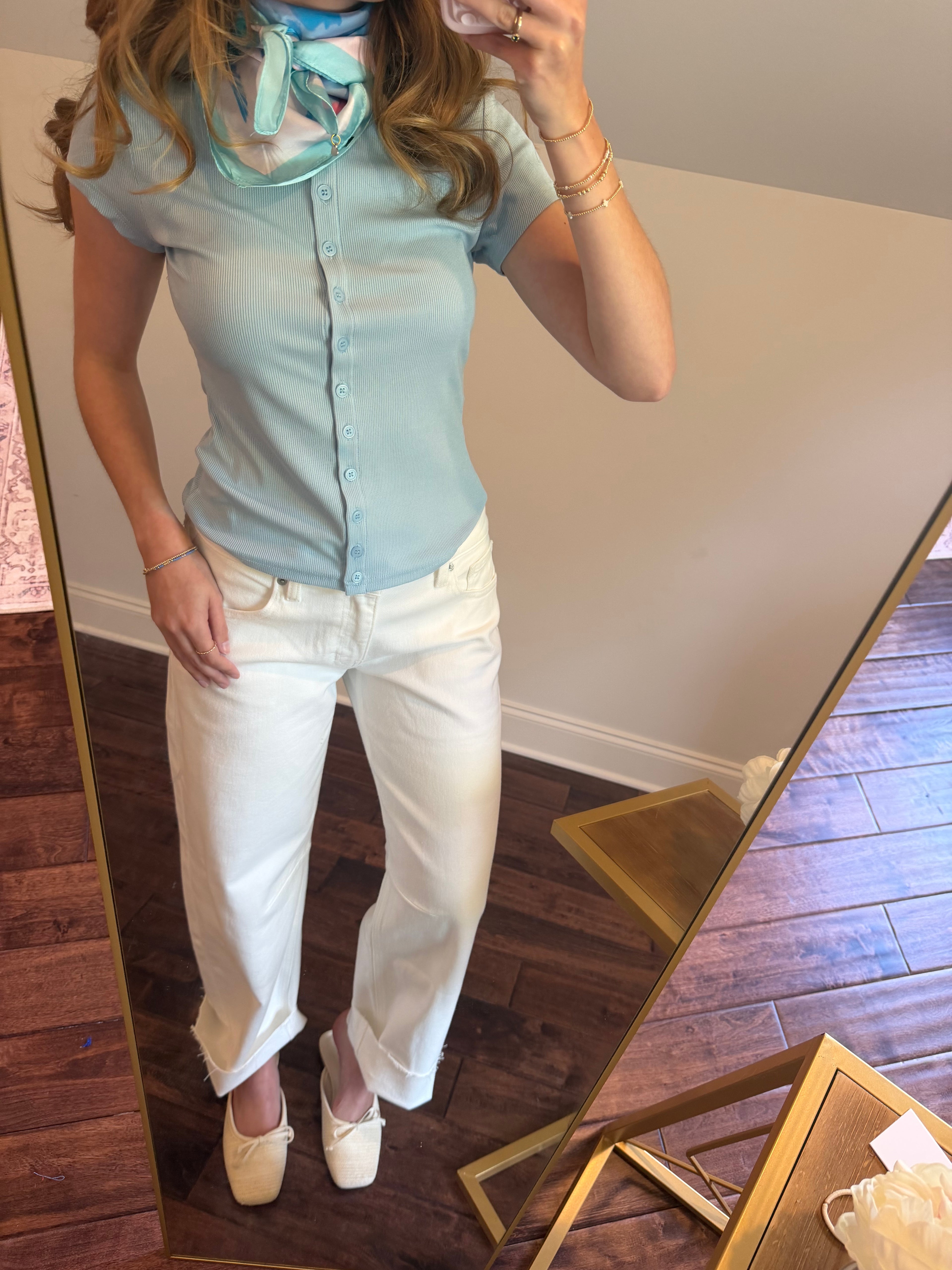 Person wearing a light blue shirt and white pants standing in front of a mirror.