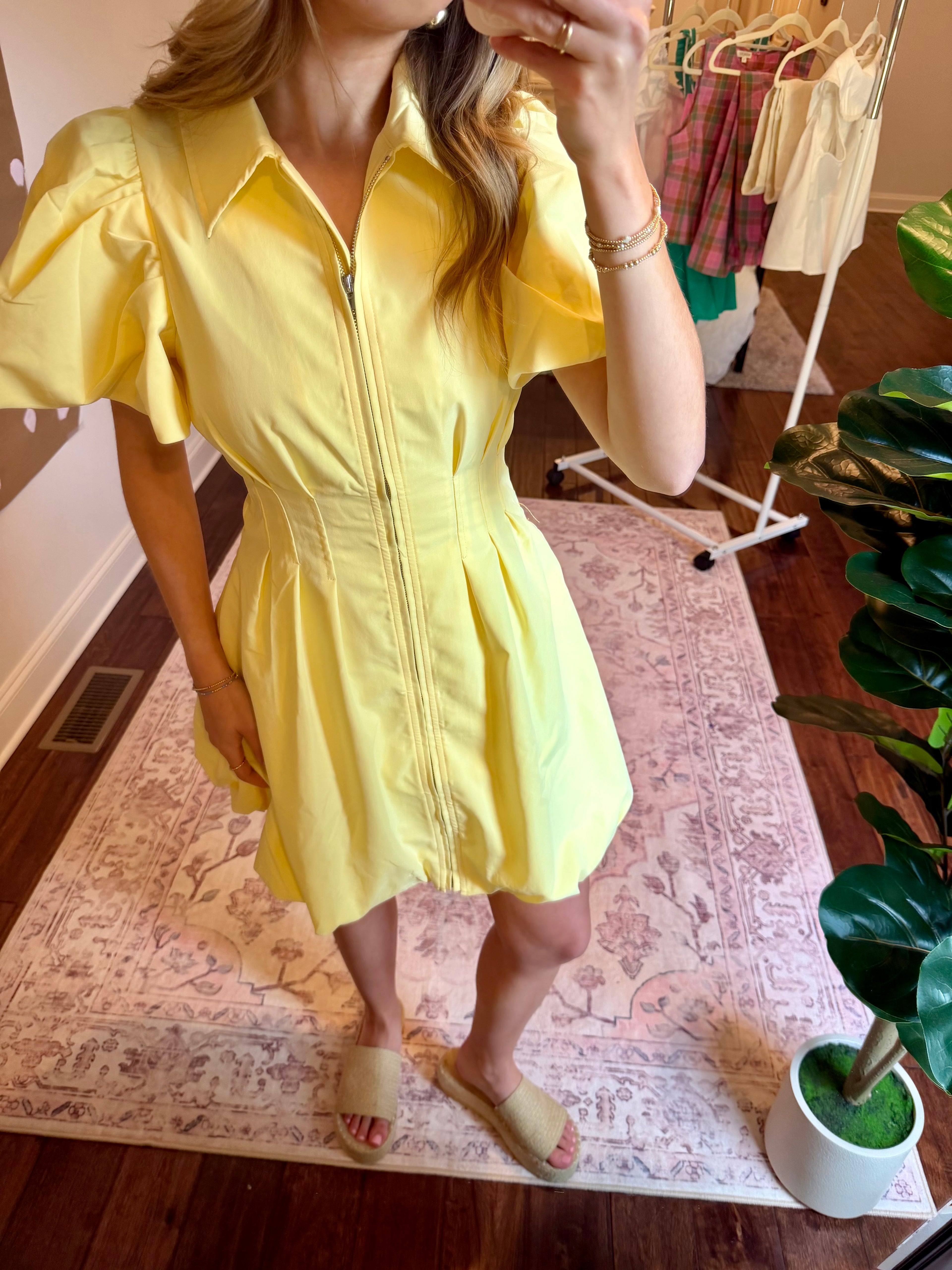 Person wearing a yellow dress standing on a patterned rug indoors.