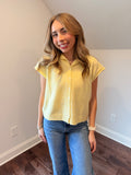 Woman wearing a yellow top and blue jeans indoors.
