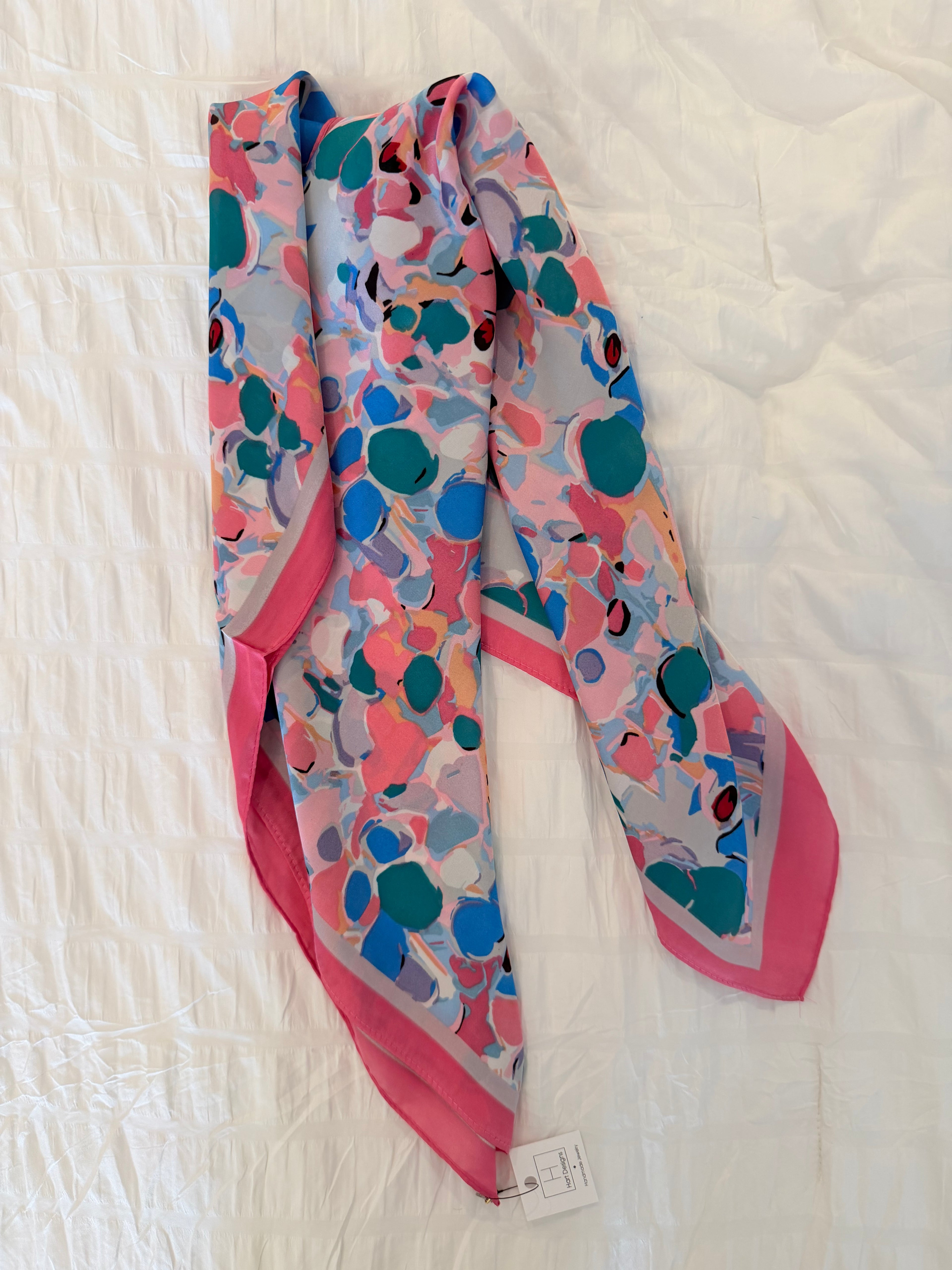 Colorful patterned scarf with pink accents on a white fabric background