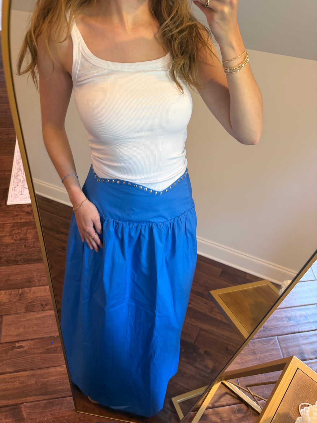 Woman wearing a white top and blue pants standing in front of a mirror.