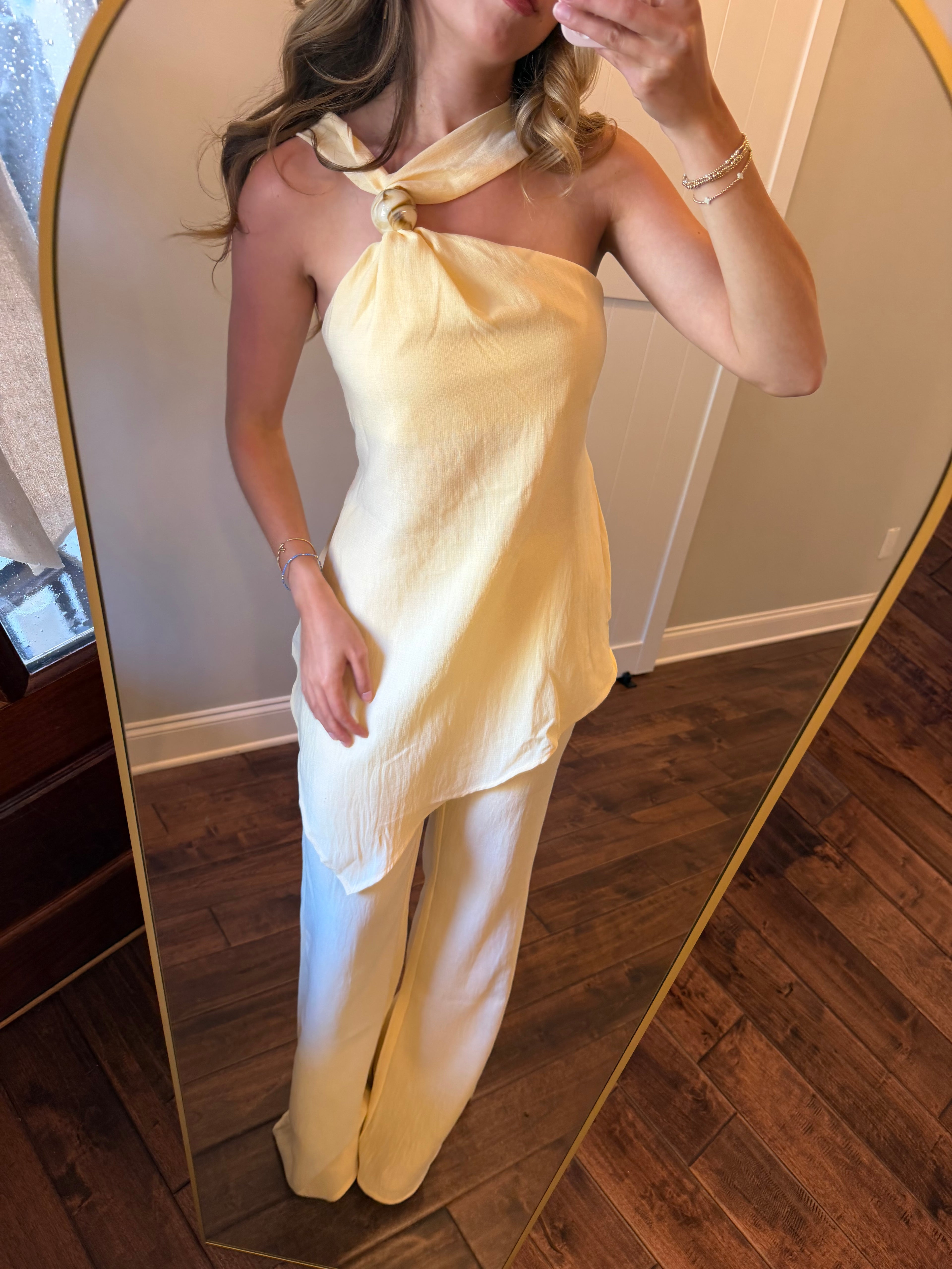 Woman in a yellow set taking a picture on a wooden floor.