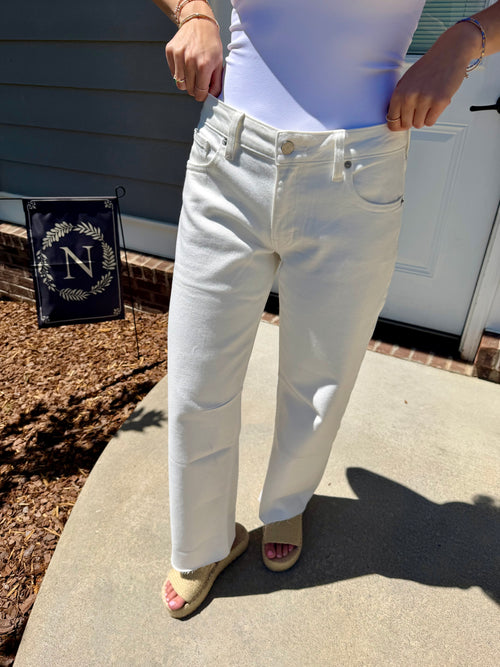Person wearing white jeans standing on a concrete step with a house in the background