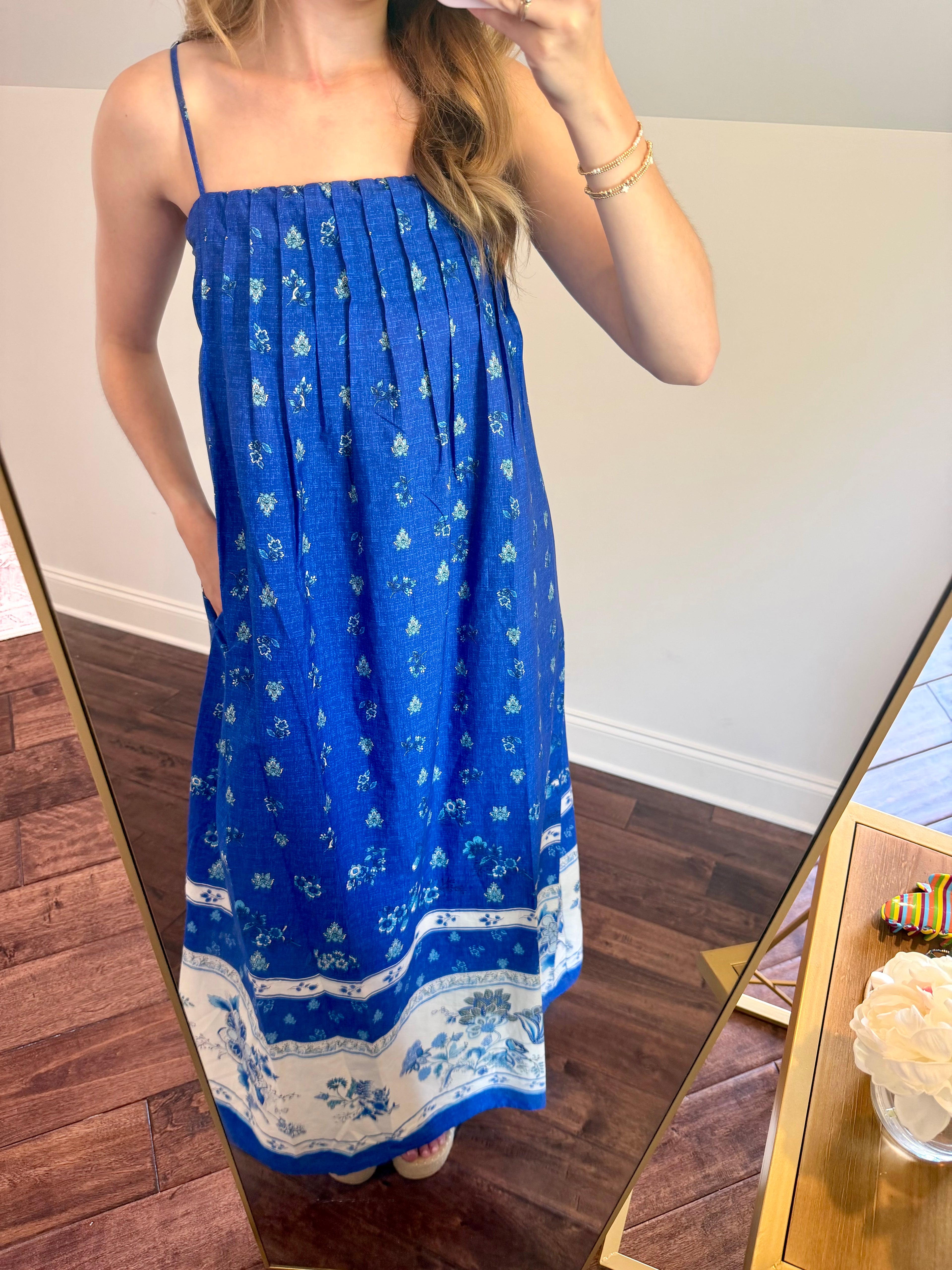 Person wearing a blue dress with white patterns in front of a mirror.