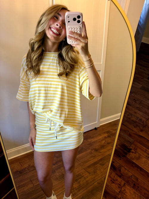 Woman taking a mirror selfie wearing a yellow and white striped dress.