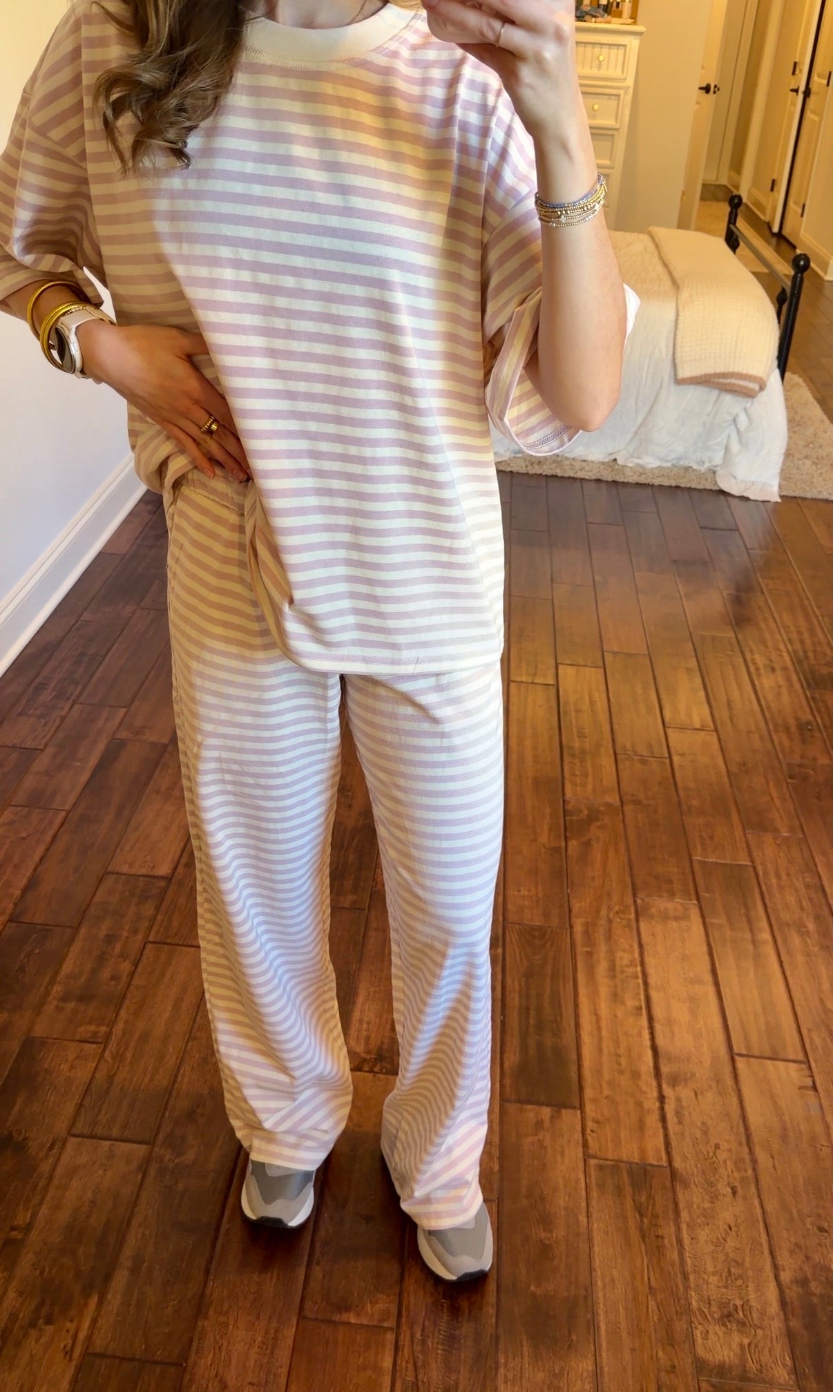 Person wearing a striped pink set in a bedroom.