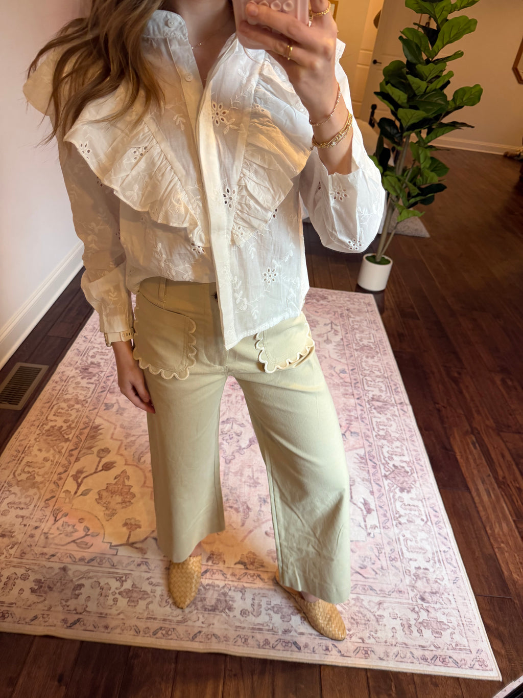 Person wearing a white blouse with beige pants and shoes on a patterned rug.