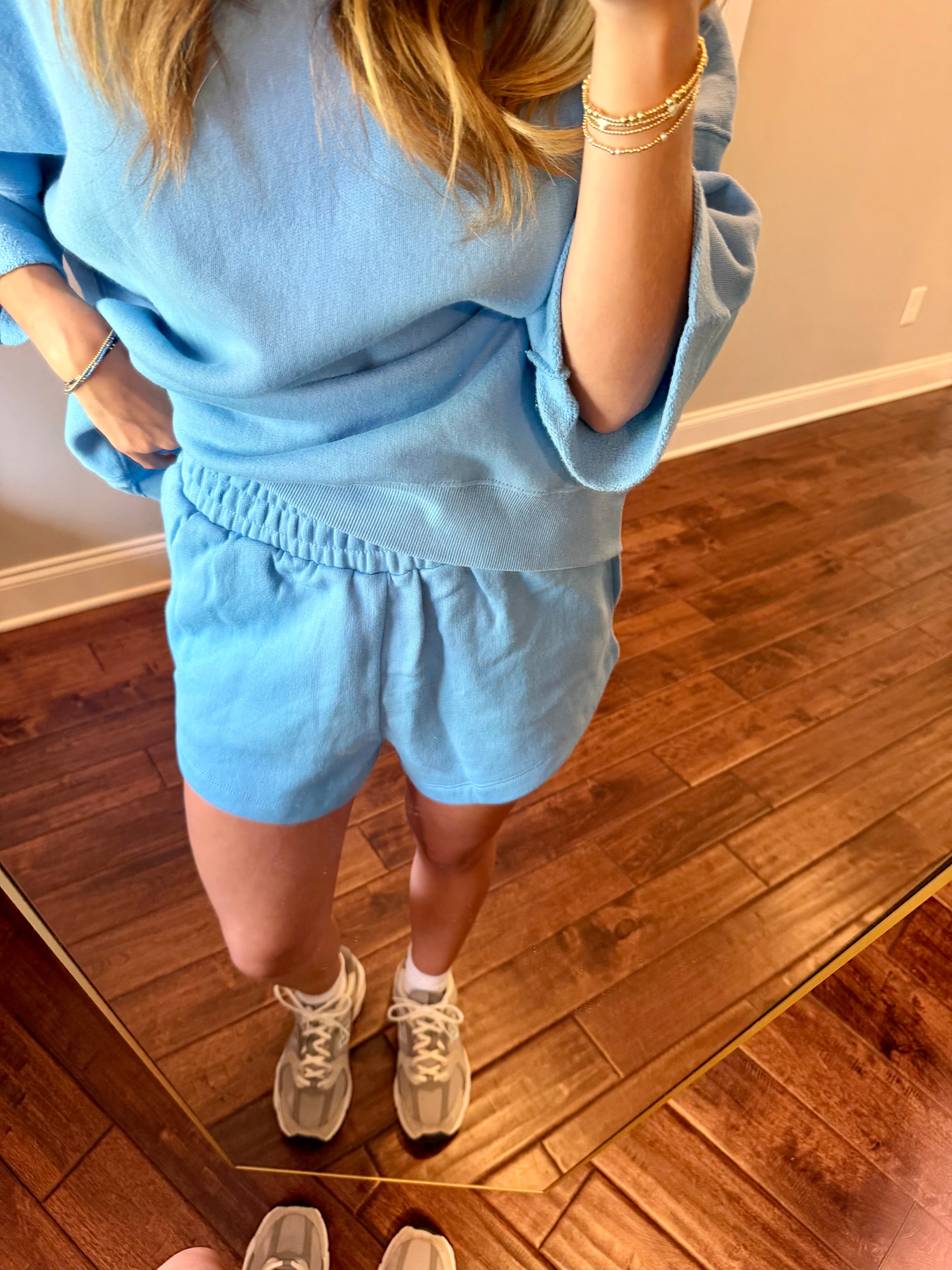 Person wearing a blue outfit standing on a wooden floor.