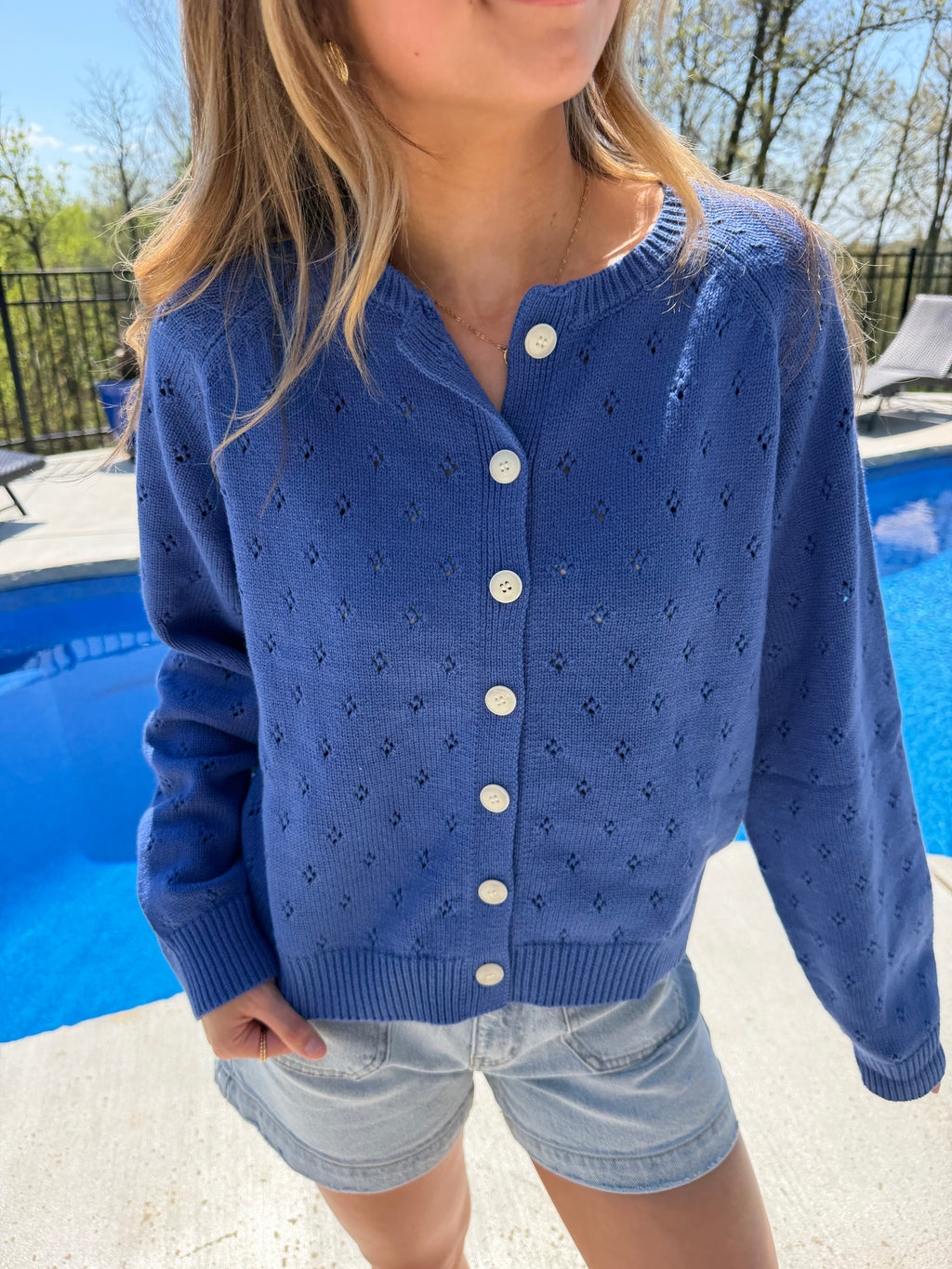 Person wearing a blue cardigan with white buttons outdoors