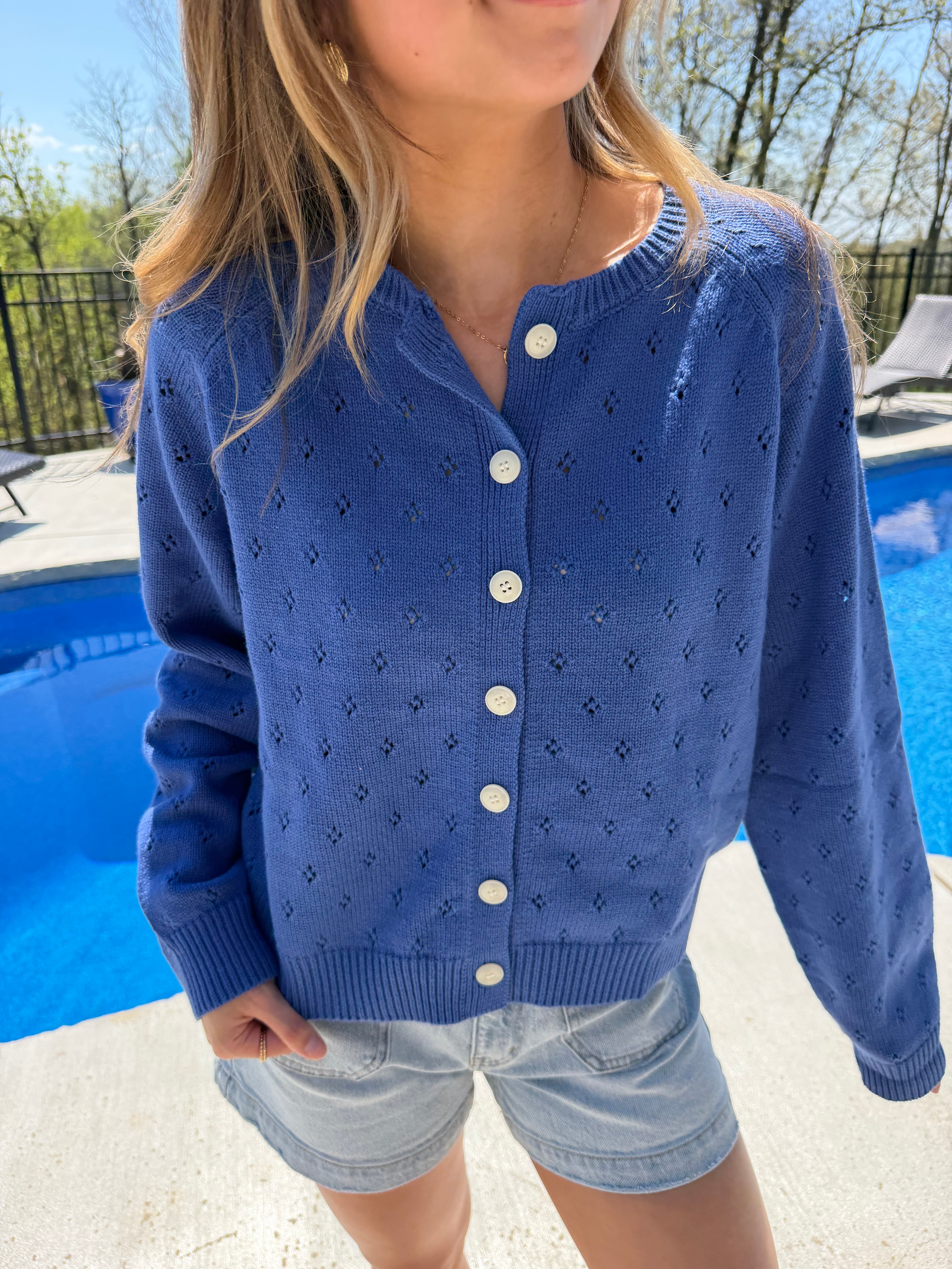 Person wearing a blue cardigan with white buttons outdoors