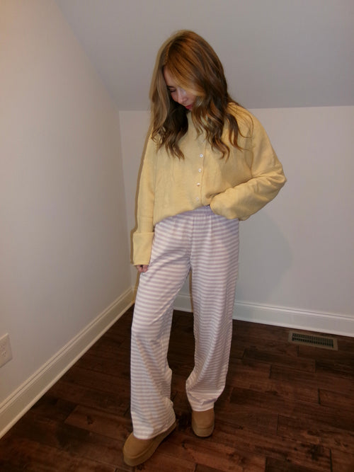 Person wearing a yellow shirt and white striped pants in a room with wooden flooring.