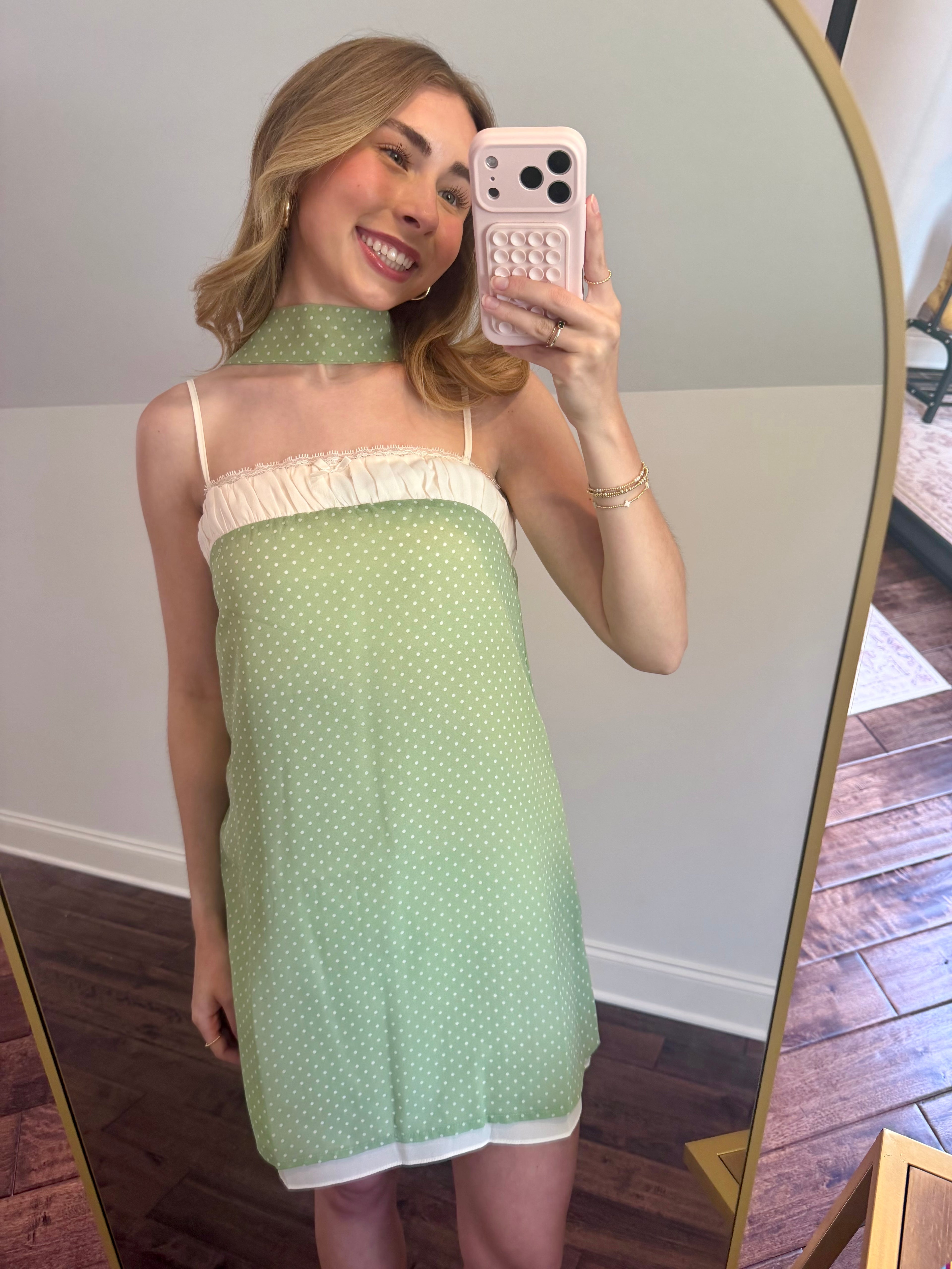 Woman taking a mirror selfie wearing a green and white dress.