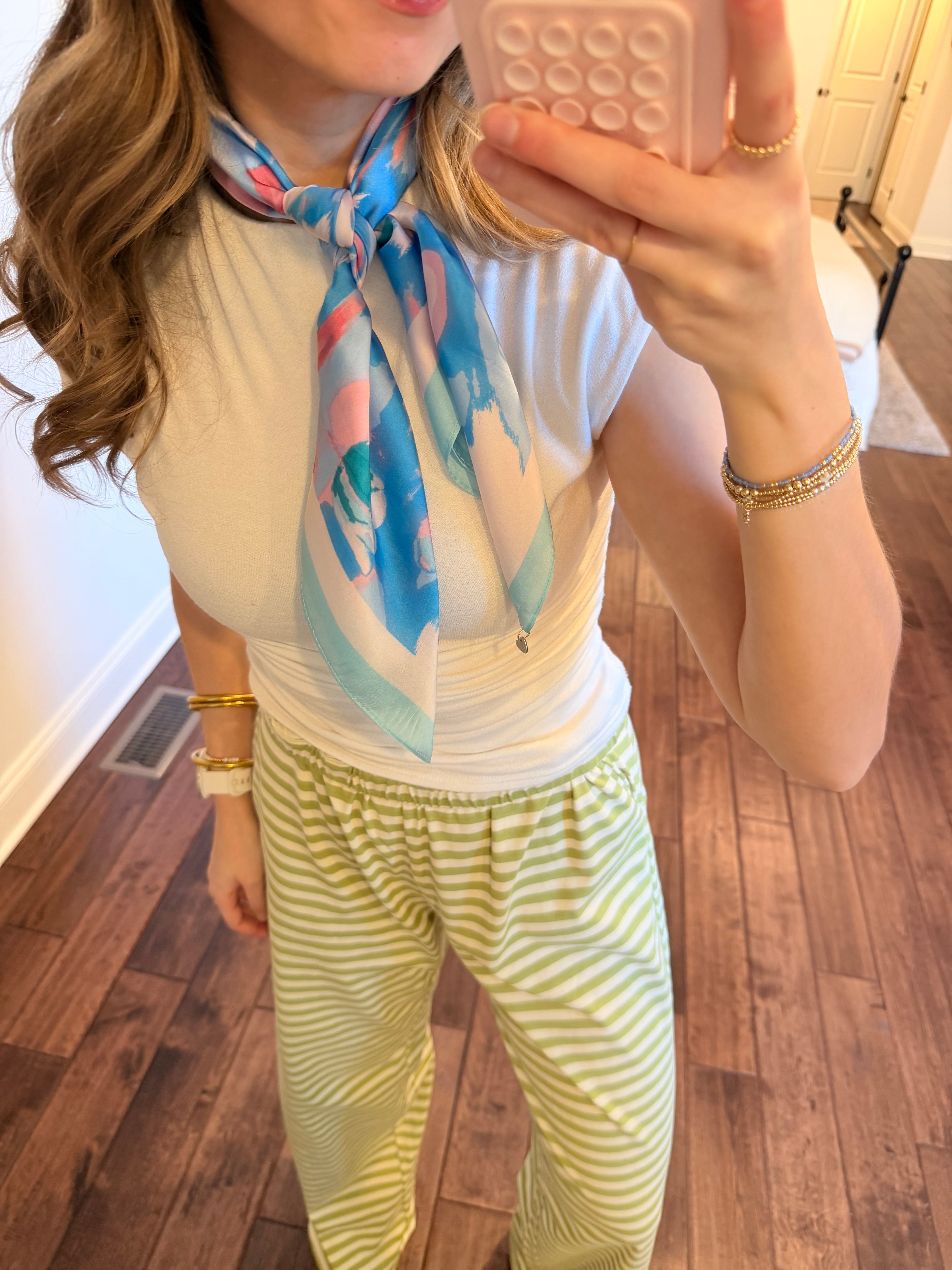 Person wearing a colorful scarf and striped pants in a room setting