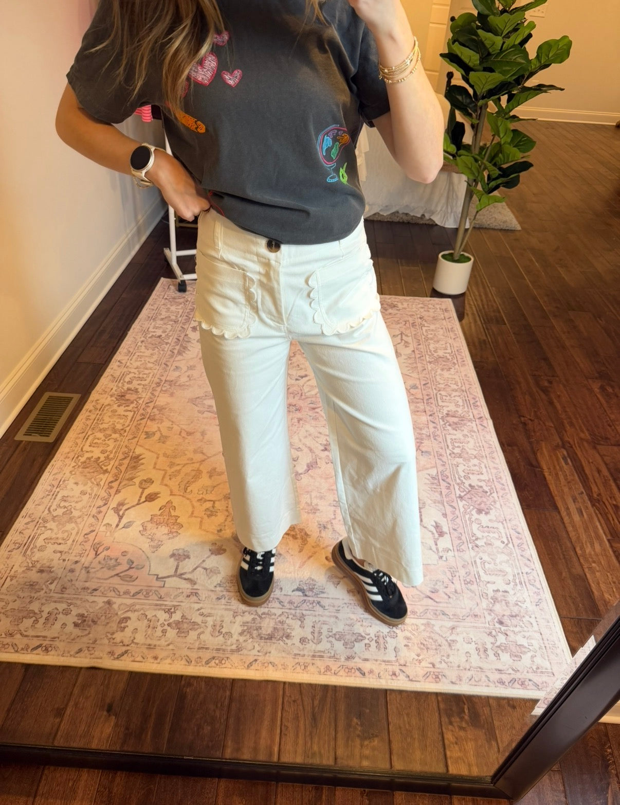 Person wearing a colorful shirt and white pants standing on a patterned rug.